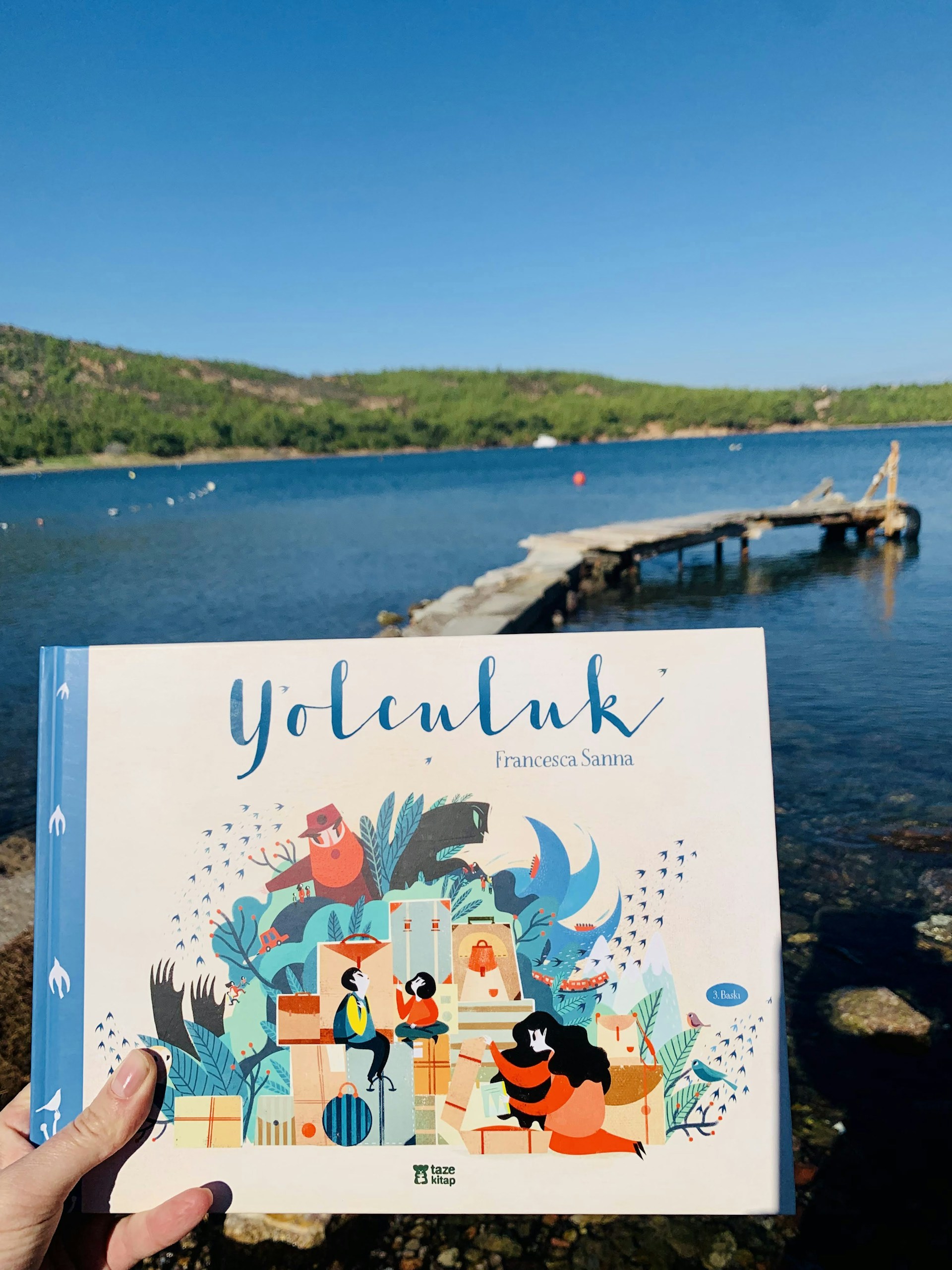 Book held in front of a serene lake landscape