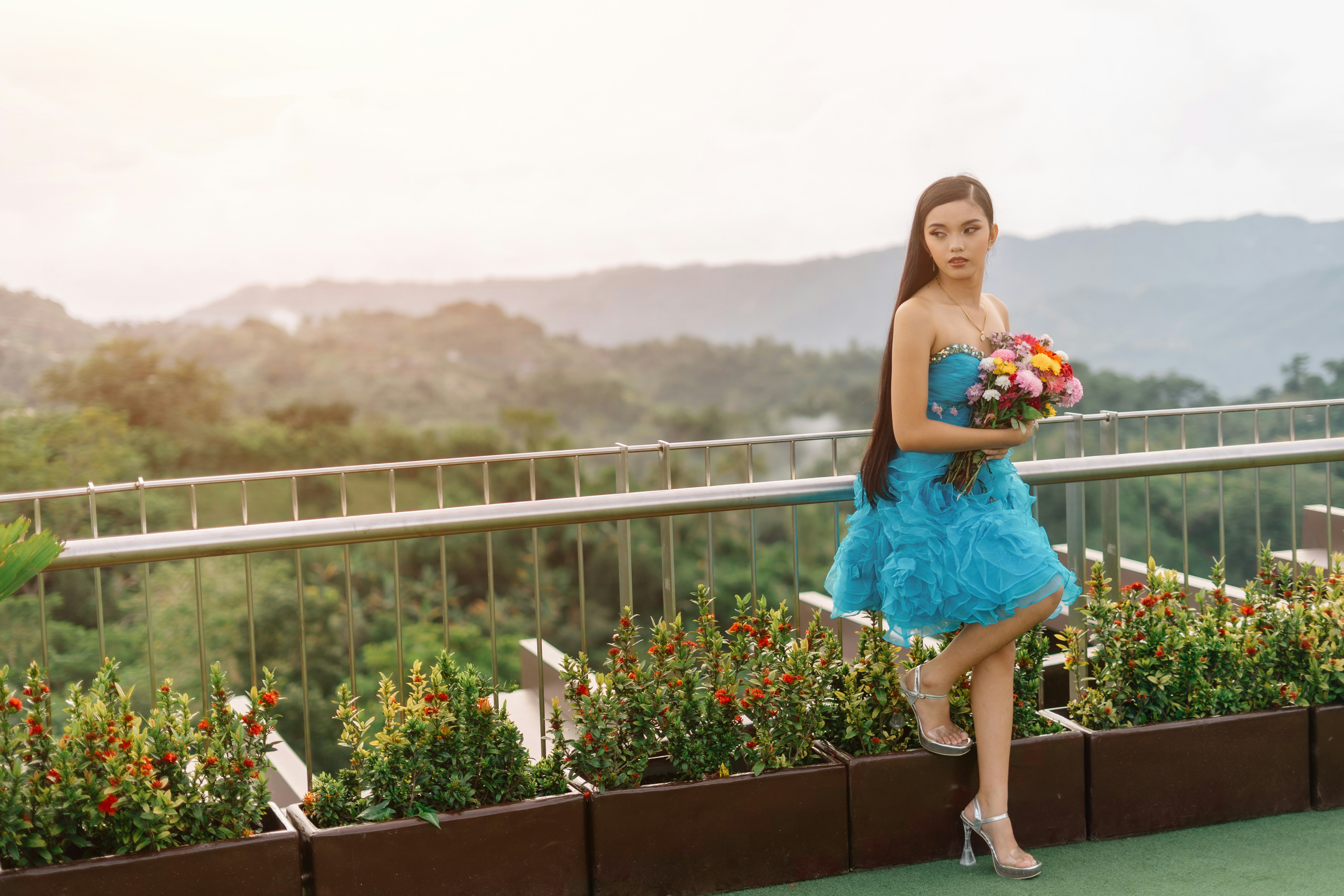 Woman in blue dress holding bouquet on rooftop