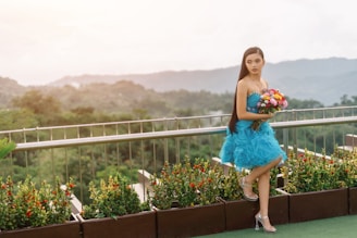 Woman in blue dress holding bouquet on rooftop