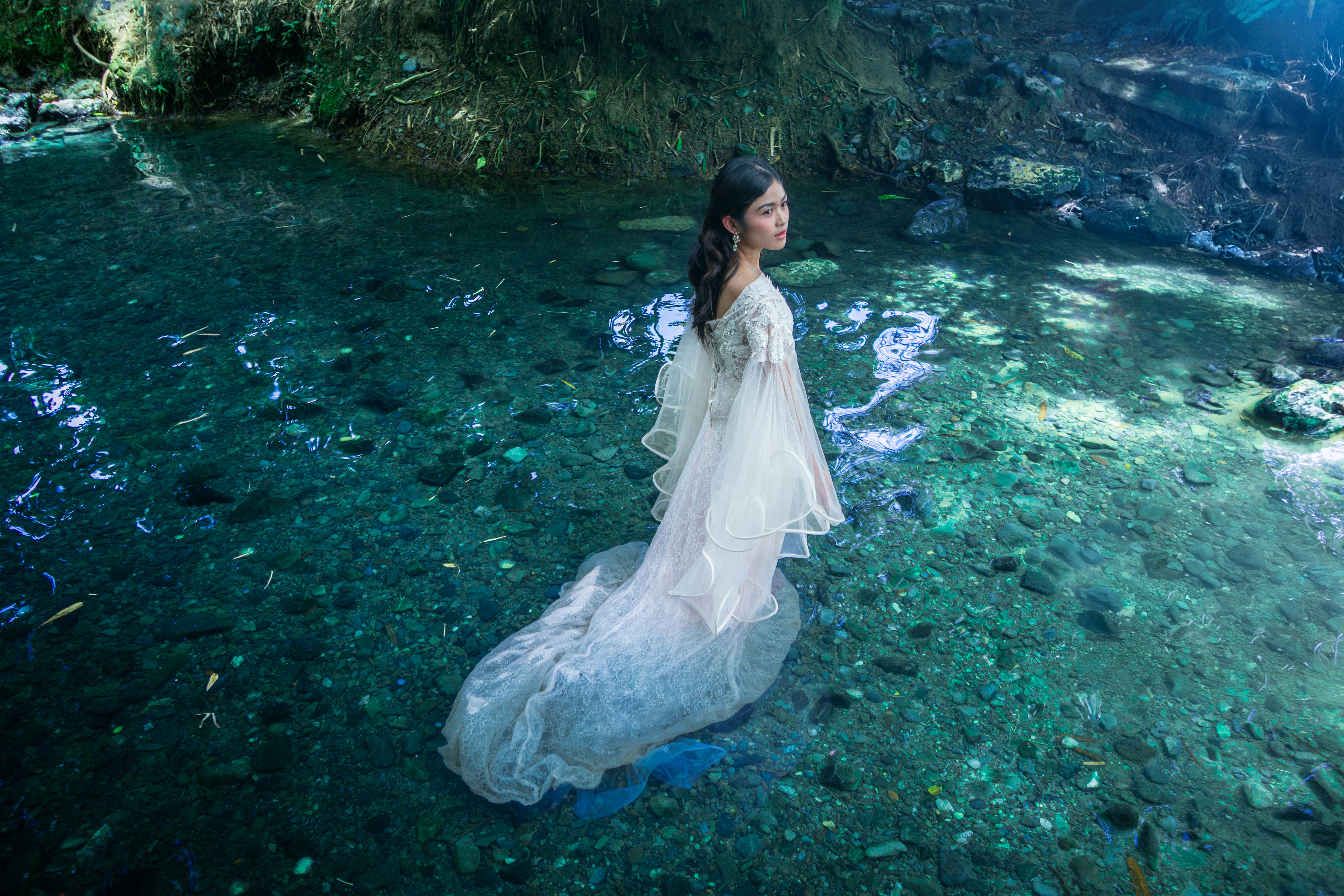 Woman in white dress standing in shallow stream