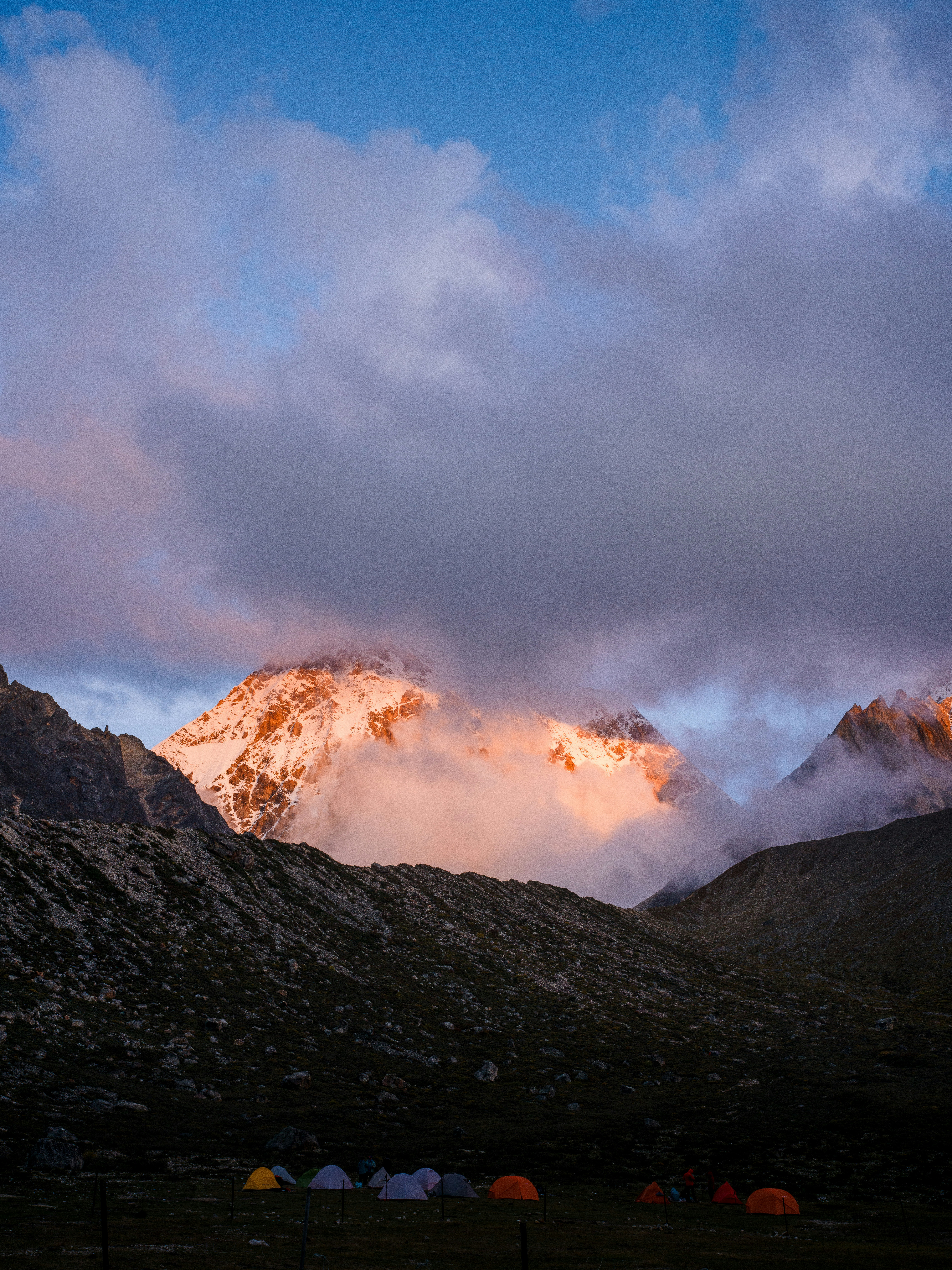 Cima della montagna innevata illuminata dall'alba, nuvole vorticose.
