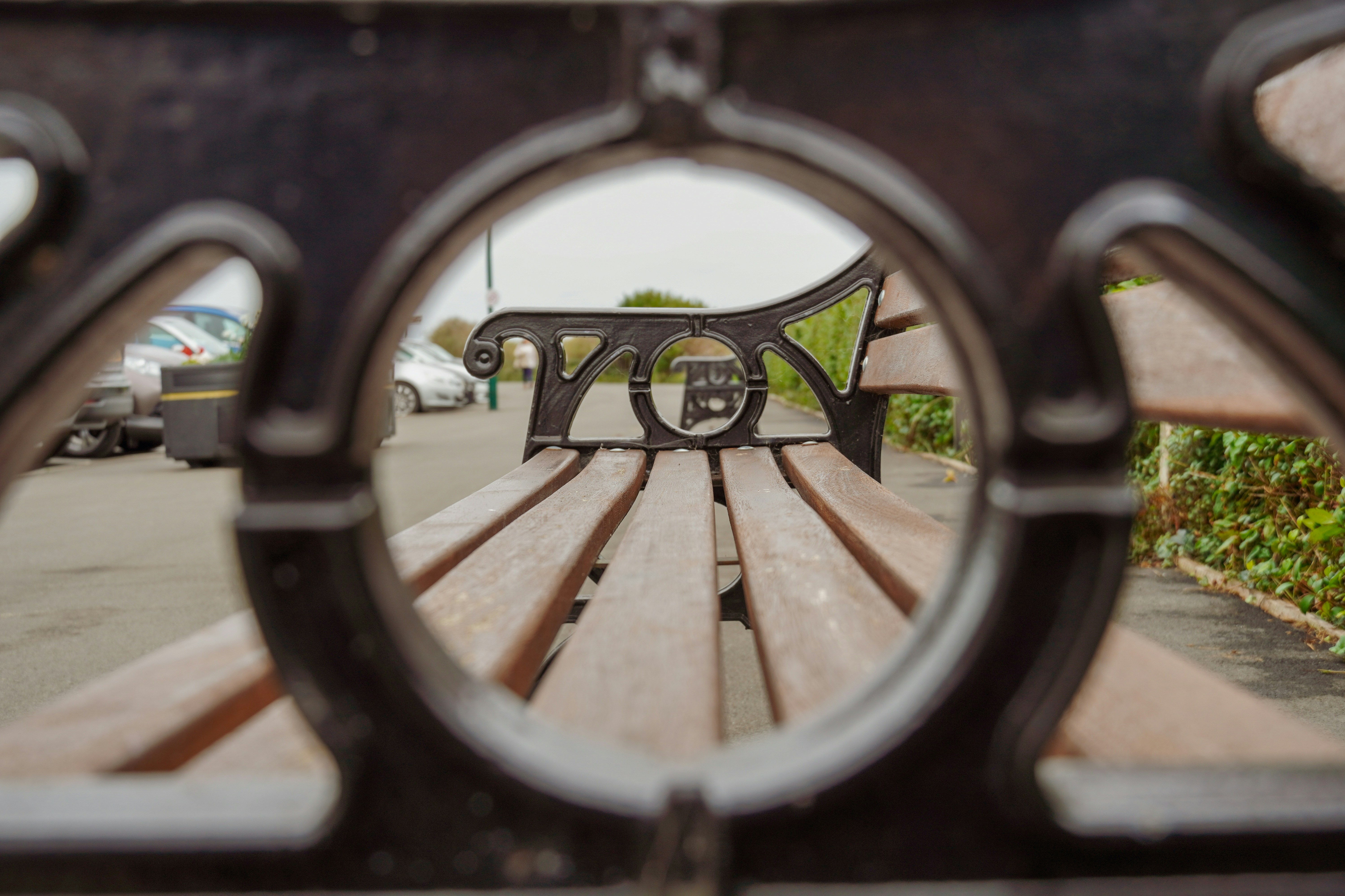 Wooden park bench viewed through ornate metal frame