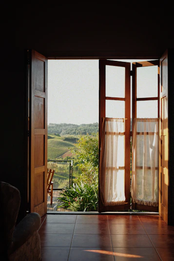 Open wooden doors reveal a green rolling landscape.