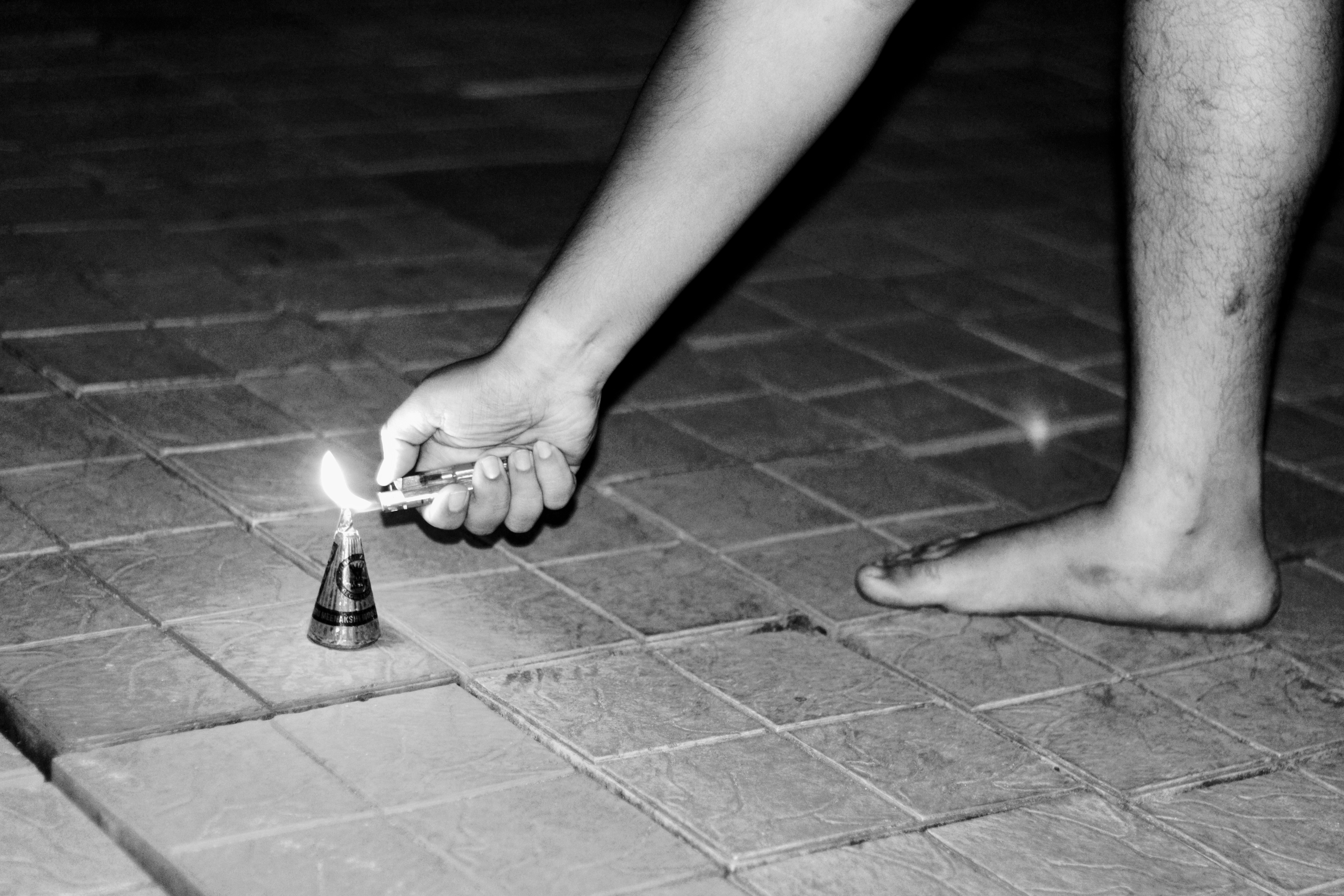 Persona encendiendo un petardo en suelo de baldosas