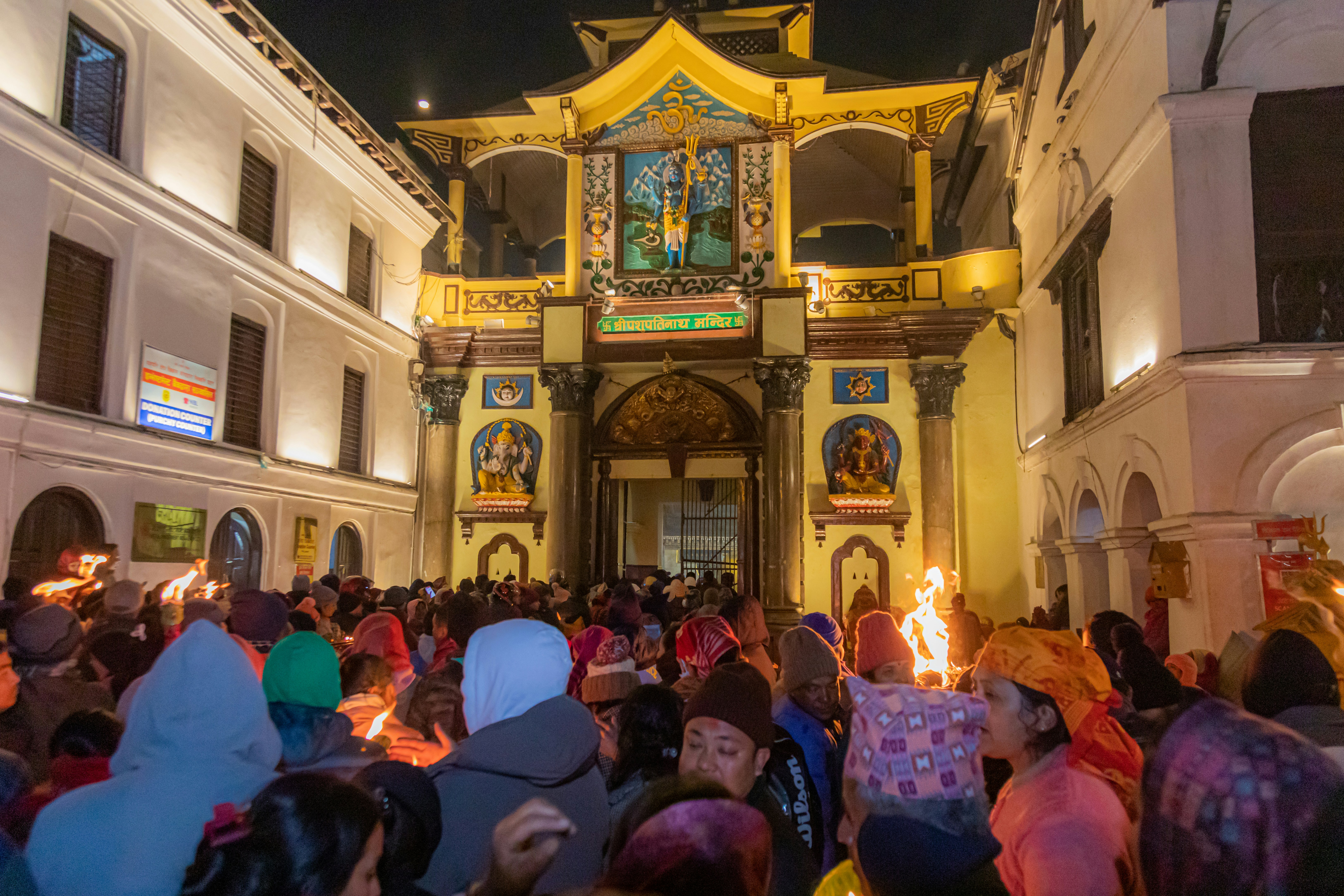 Crowd gathered at a brightly lit temple at night
