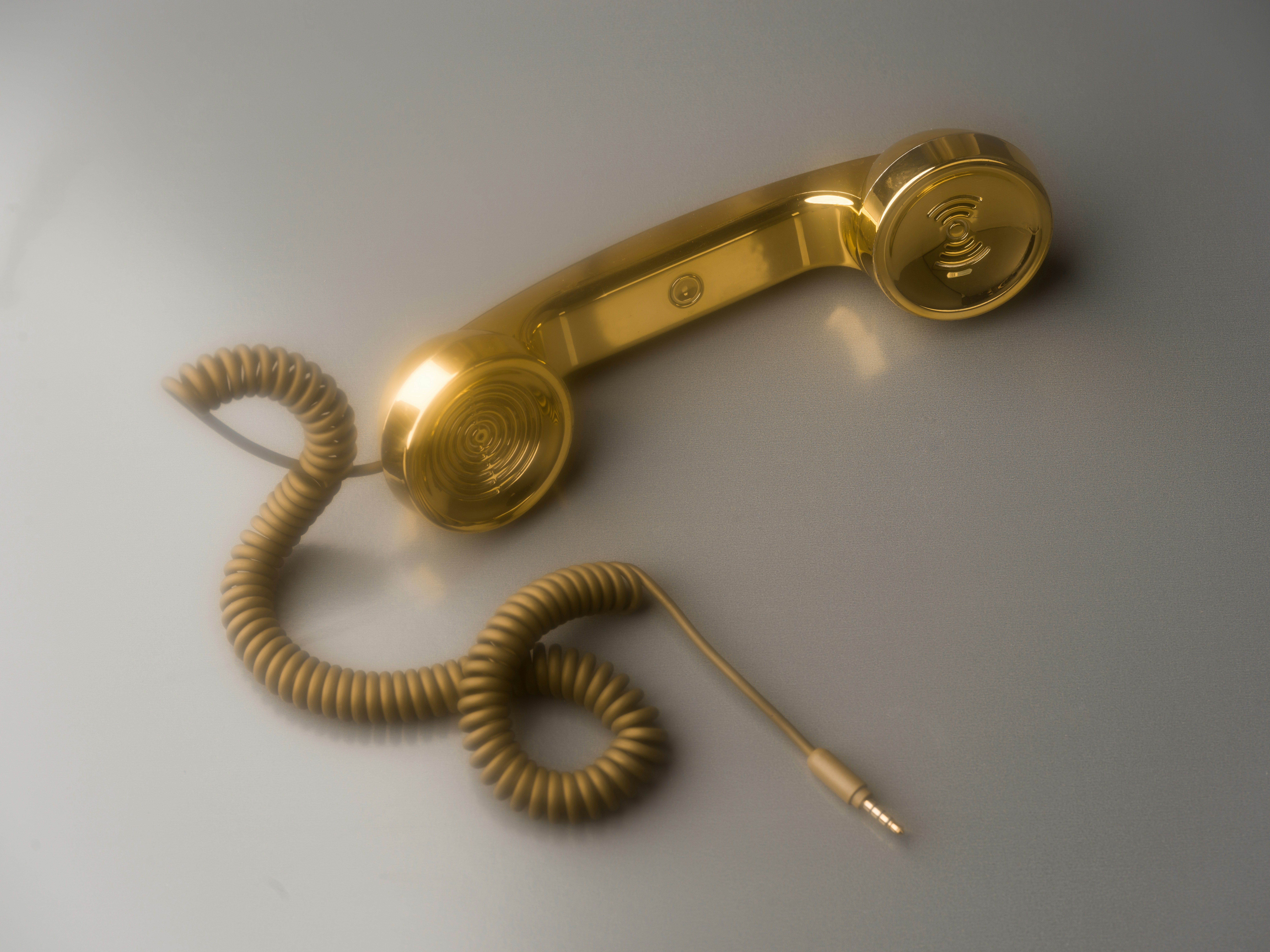 Shiny gold telephone receiver with coiled cord