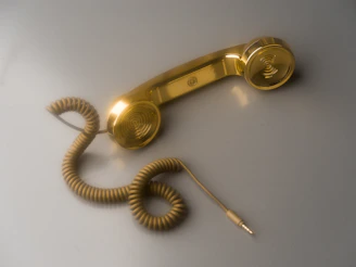 A shiny gold telephone receiver with coiled cord