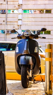 A black vespa scooter parked in front of a building.