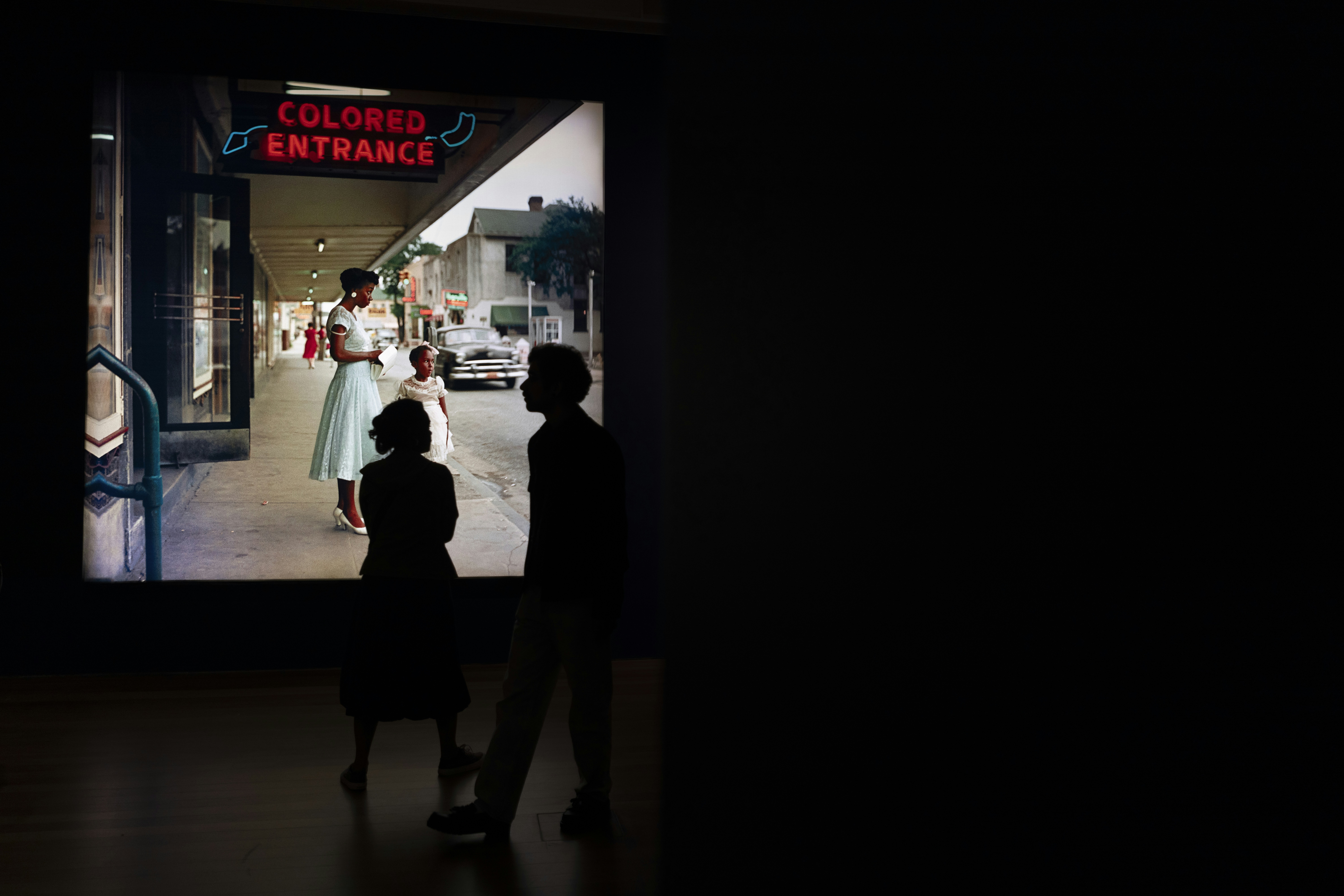 People walk past a "colored entrance" sign.