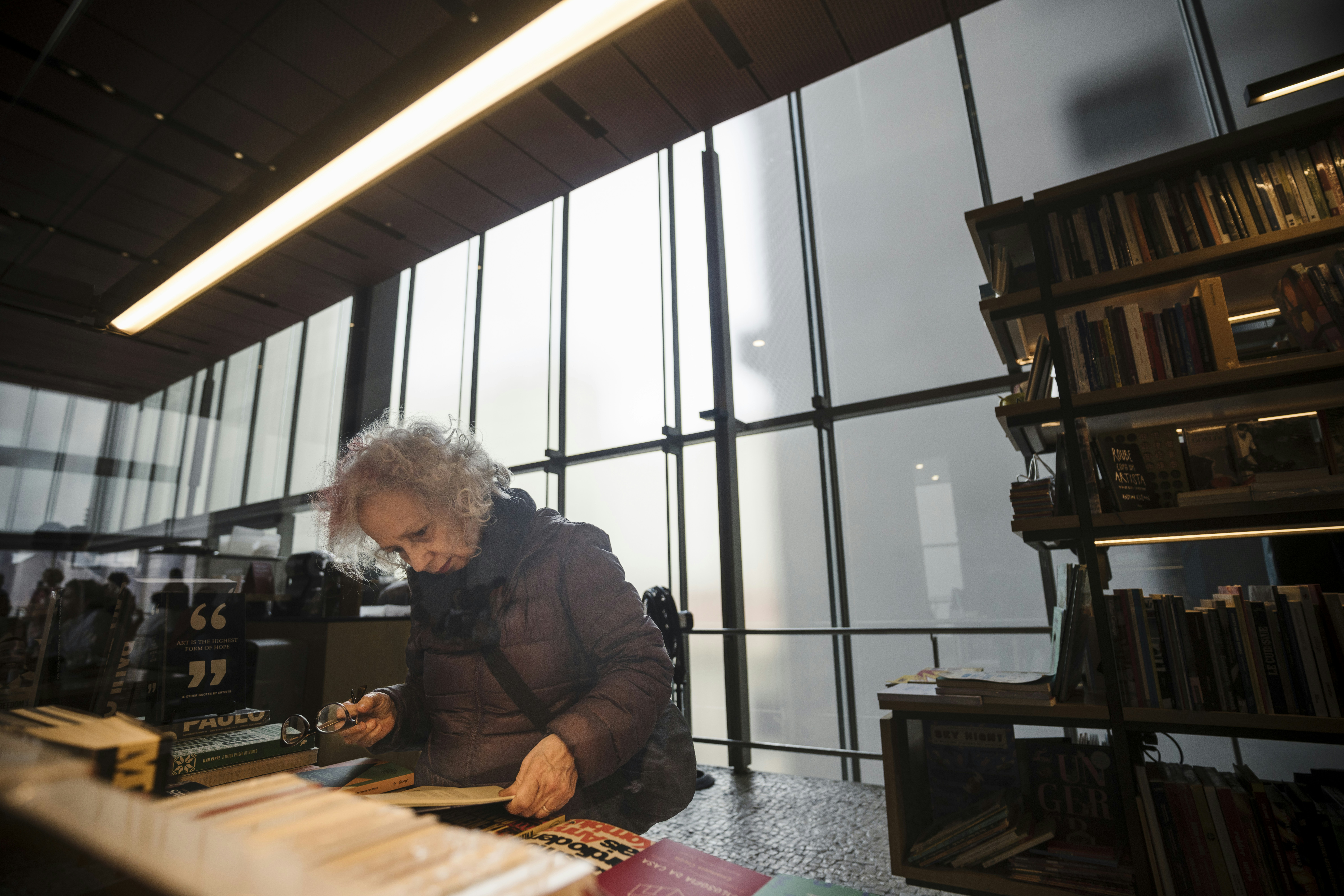 Elderly woman working at a desk in library.