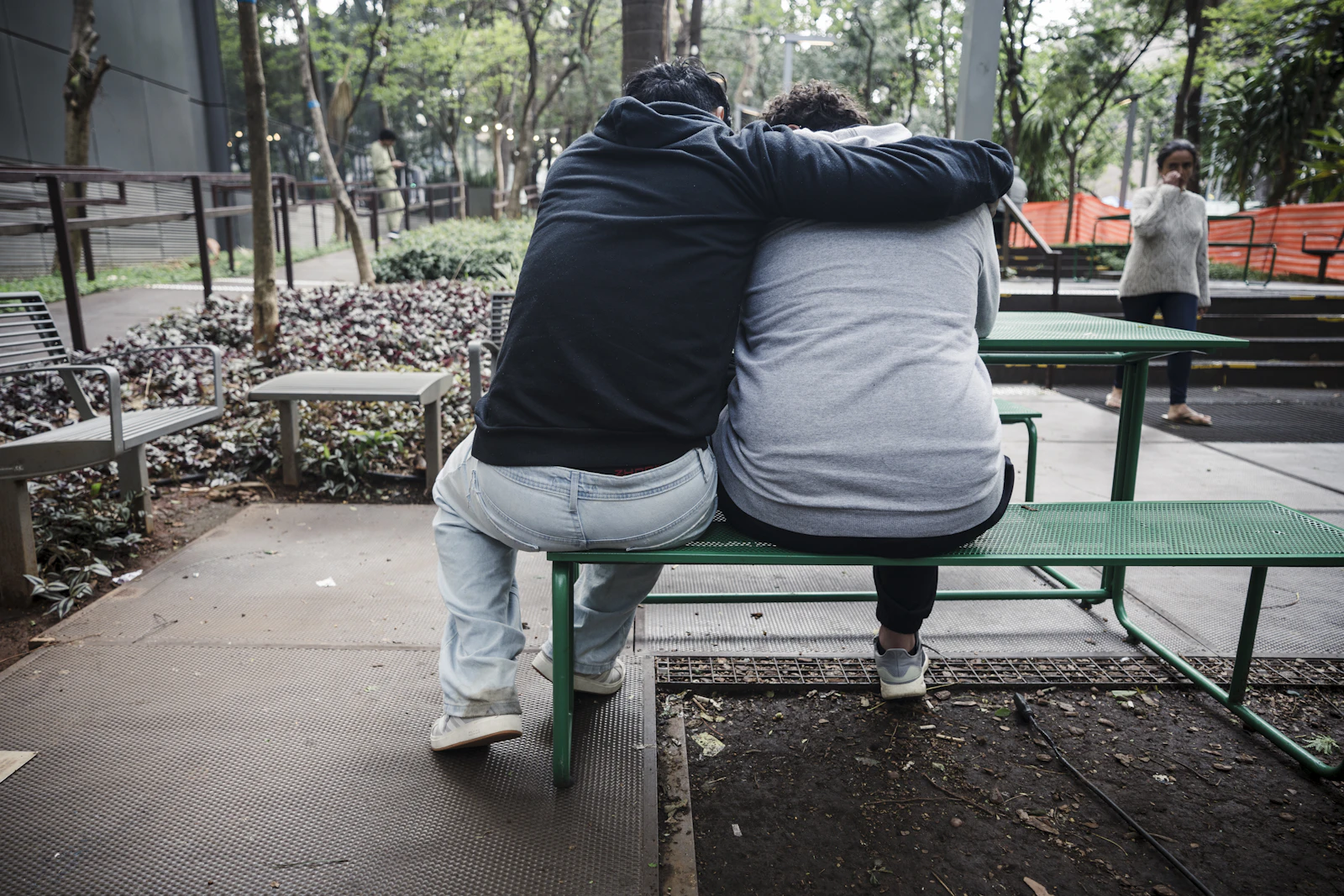 Two friends sitting close together on a park bench