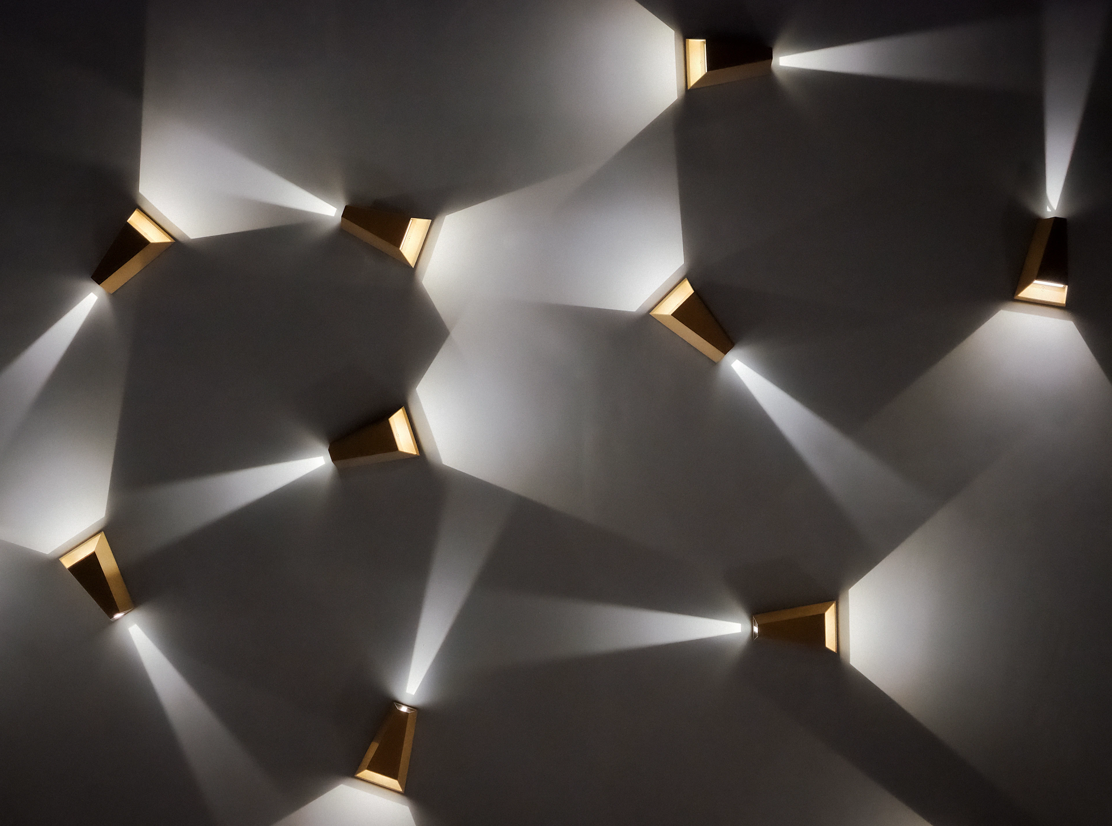 Modern wall lights casting geometric light patterns across a grey wall