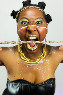 Woman with gold makeup and chains screams.