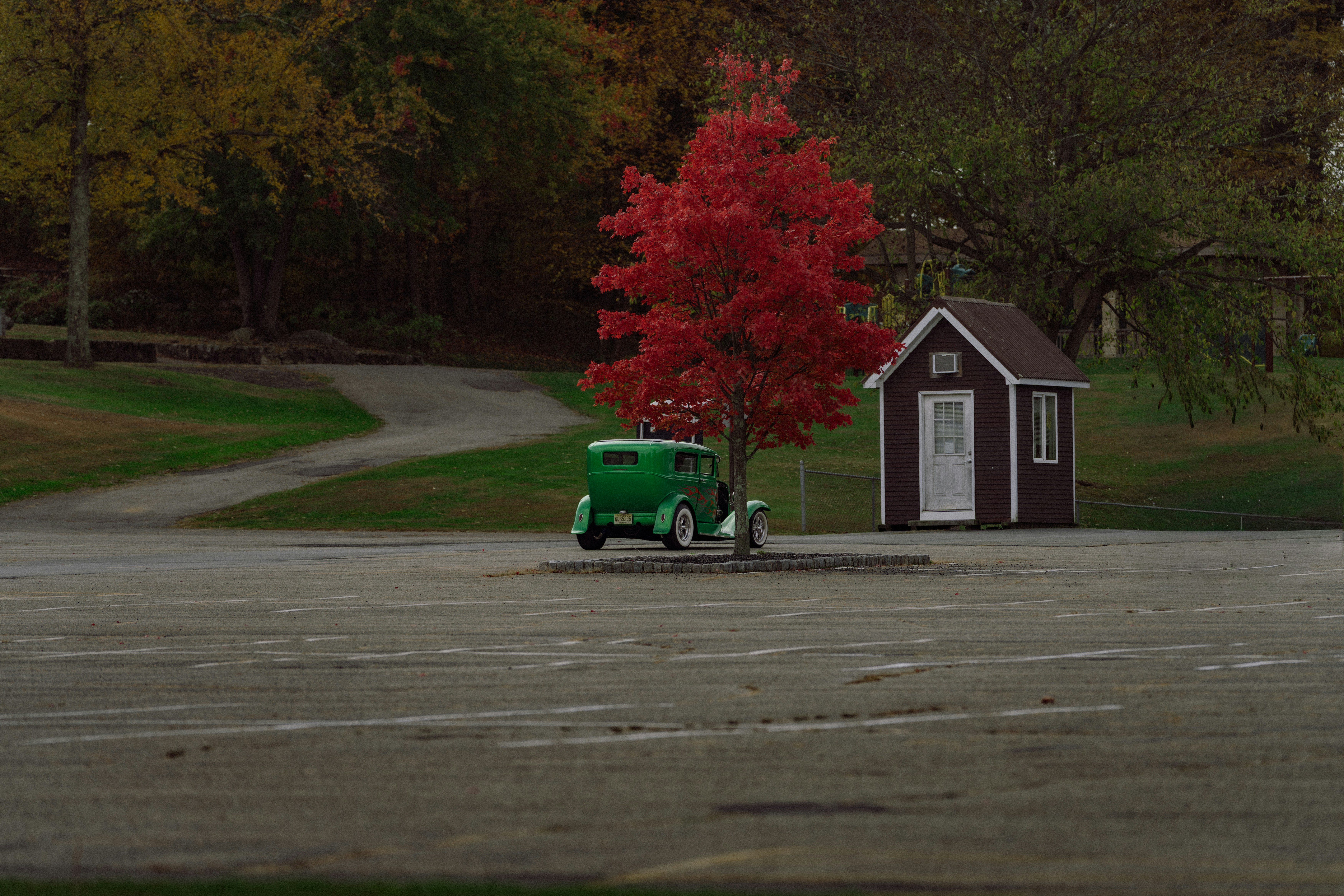 Green vintage car parked near small shed