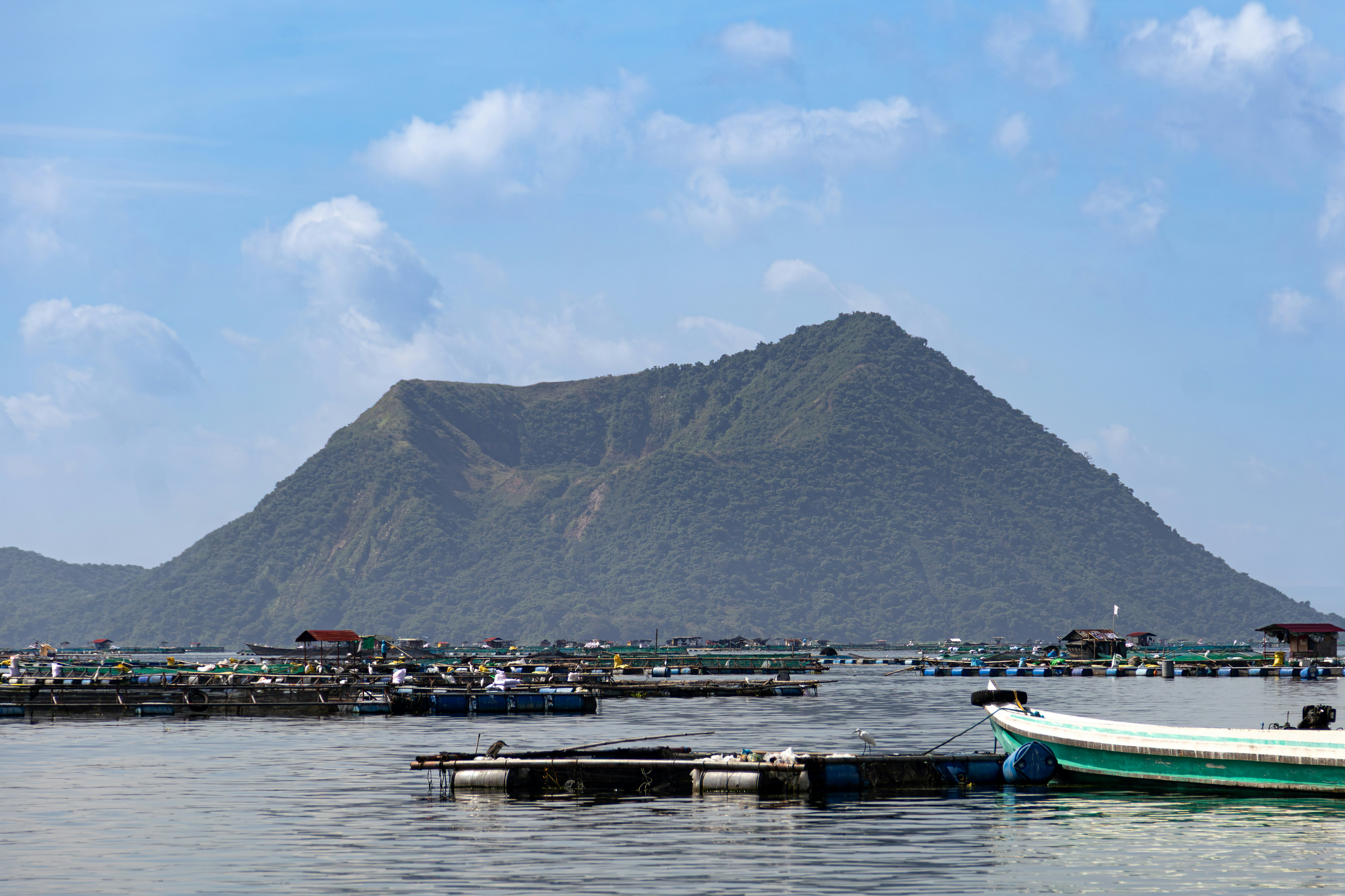 Volcanic island with fish farms in the foreground.