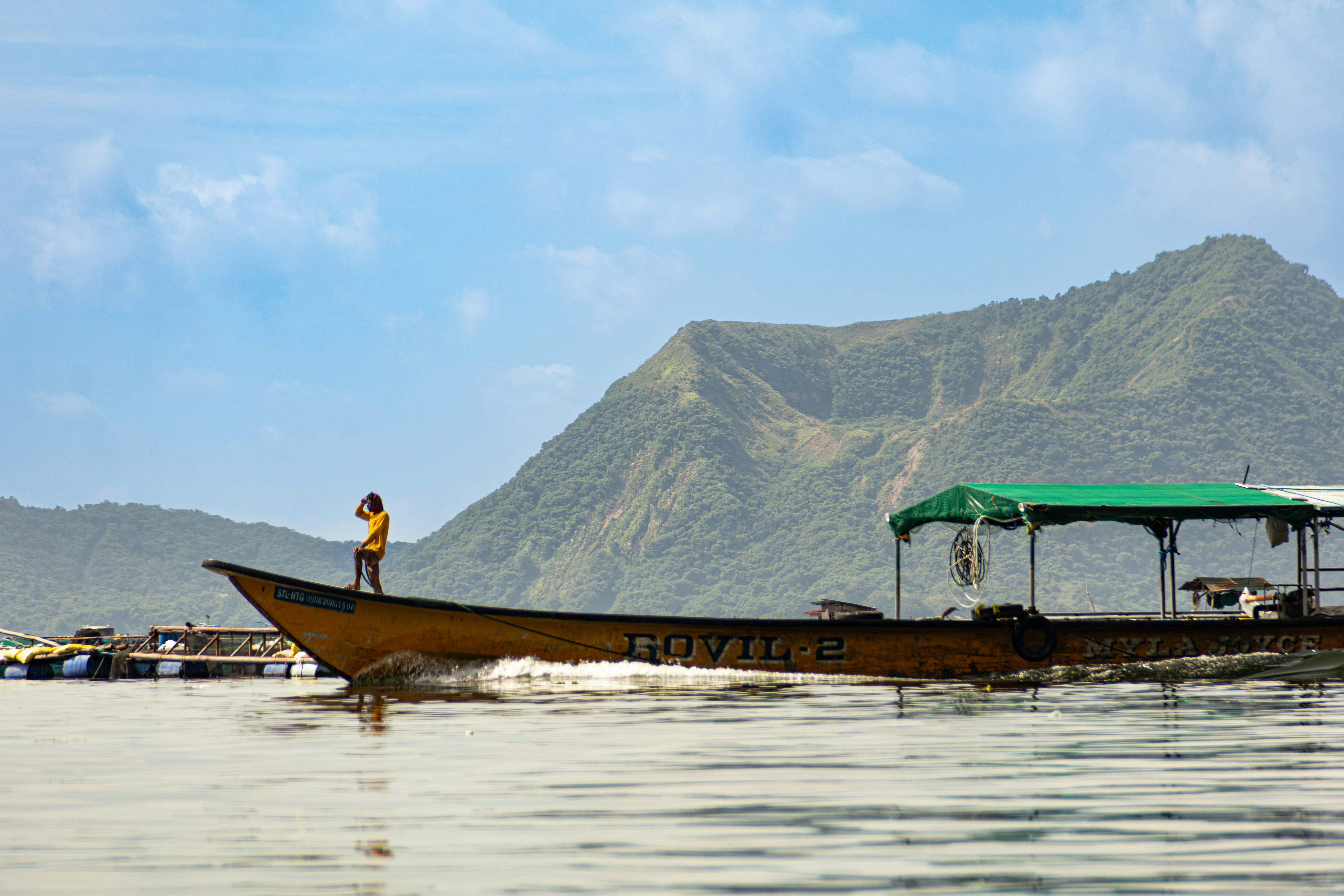 Person standing on a boat with mountains behind