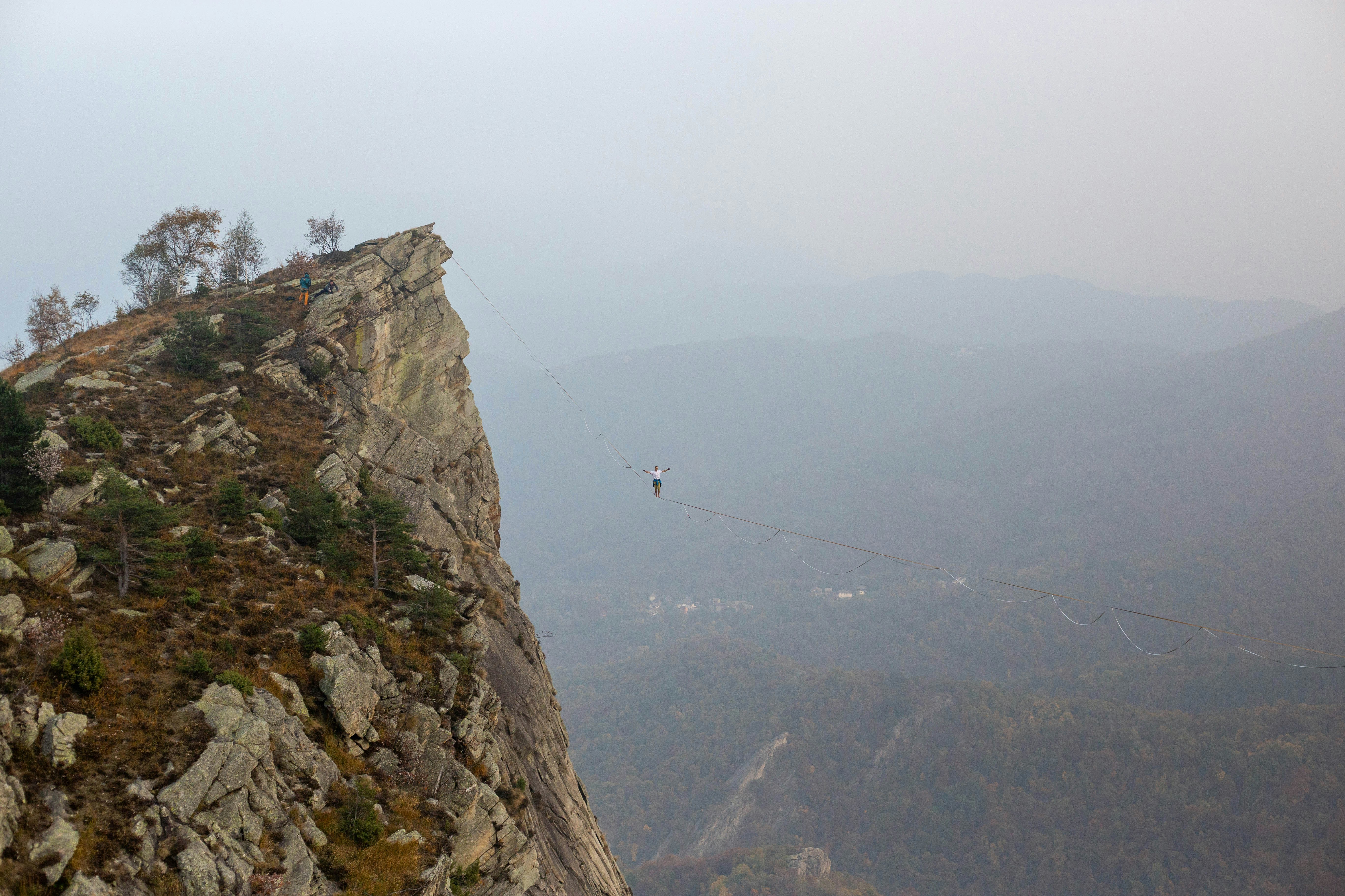A person walks on a tightrope between two cliffs.