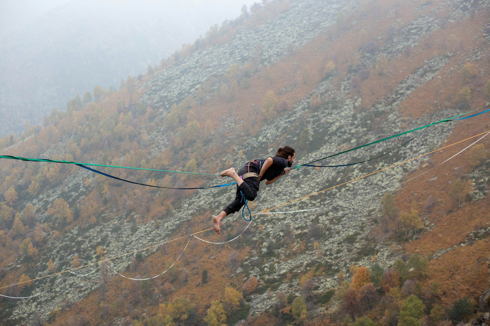 Person balancing on a slackline high above trees