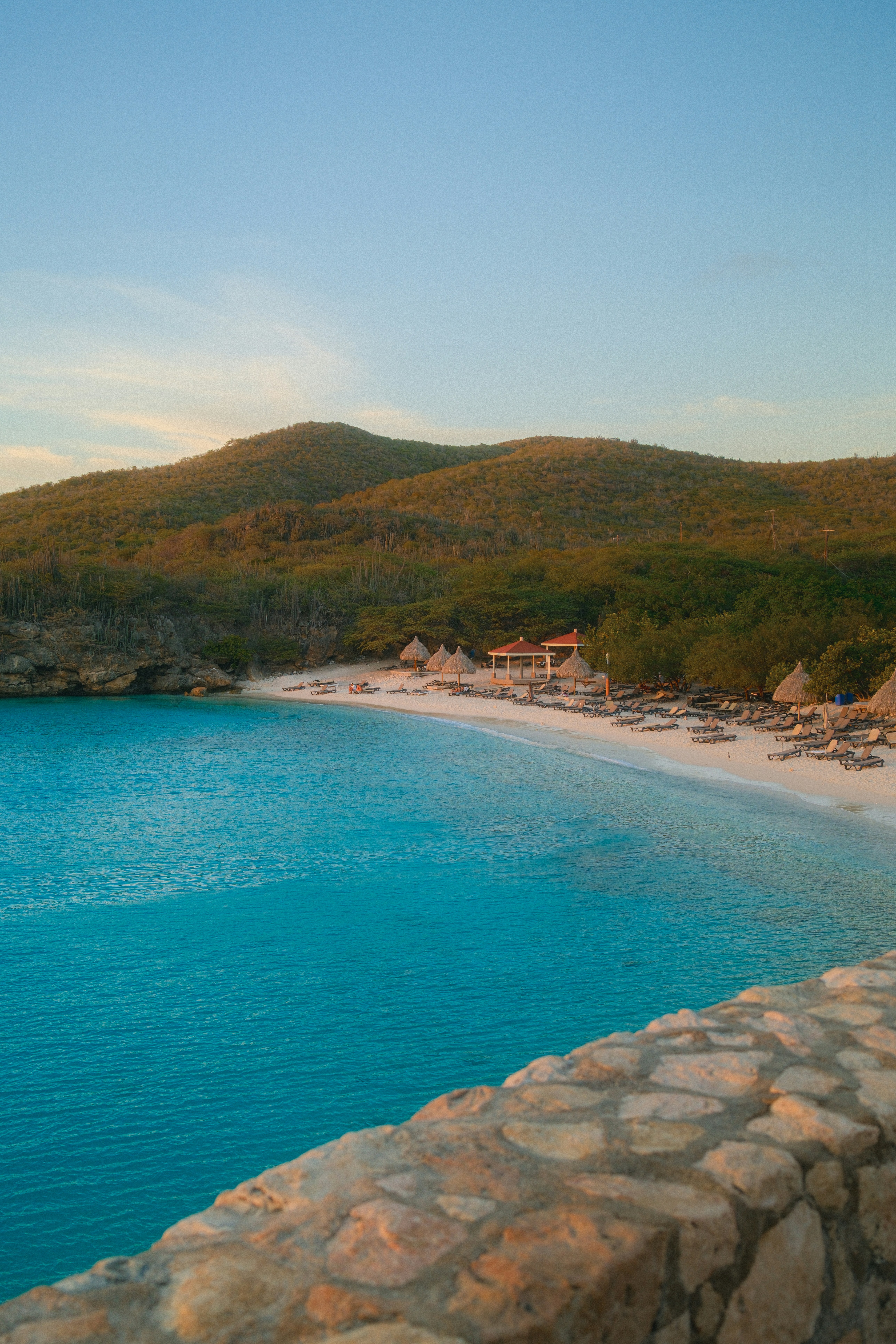 Une plage sereine avec une eau turquoise et des collines verdoyantes.