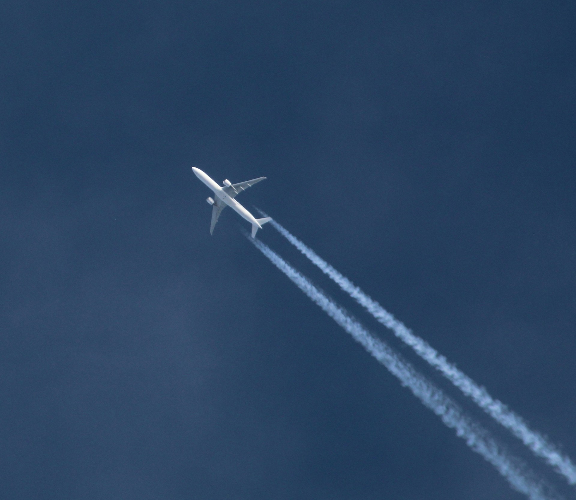 A white airplane flying through a clear blue sky.