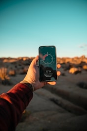 Hand holding phone with compass app in desert
