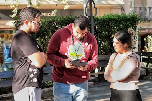 Three people looking at a tablet outdoors device outdoors
