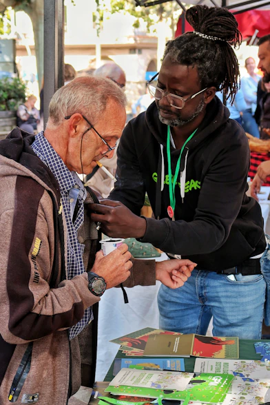 Man attaches a pin to another man's jacket.