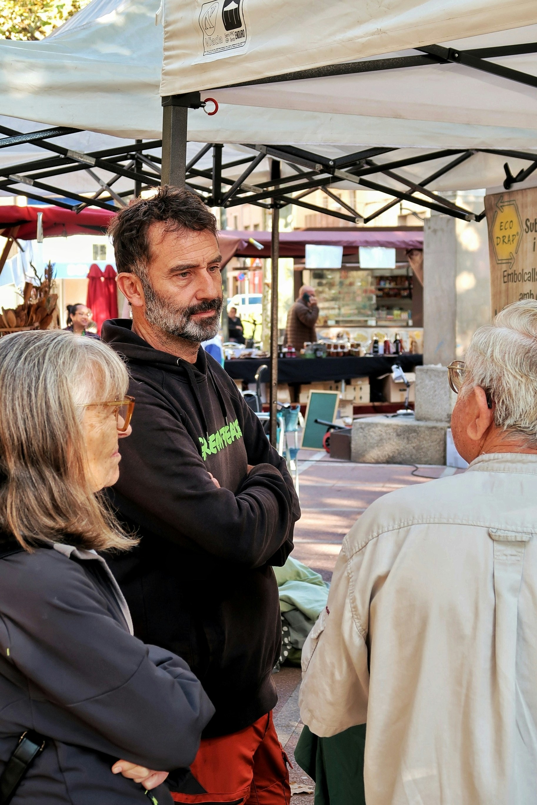 Three people talking at an outdoor market.