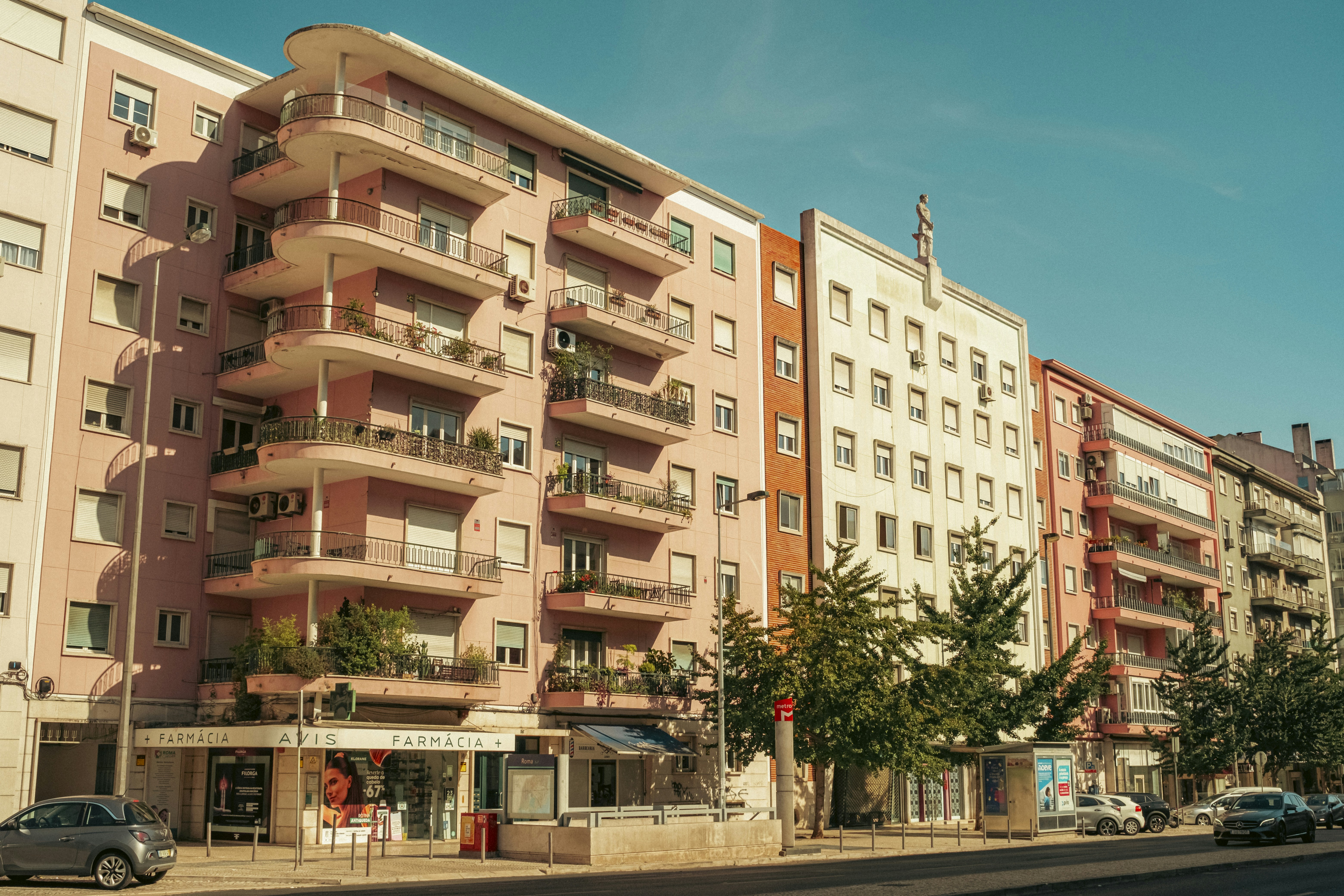 A pink apartment building at Avenida de Roma, 56 in Lisbon, Portugal. Near an exit from Roma metro station. Photo made in Summer 2025. Shot with Fujifilm XM5 and Viltrox 25/1.7
