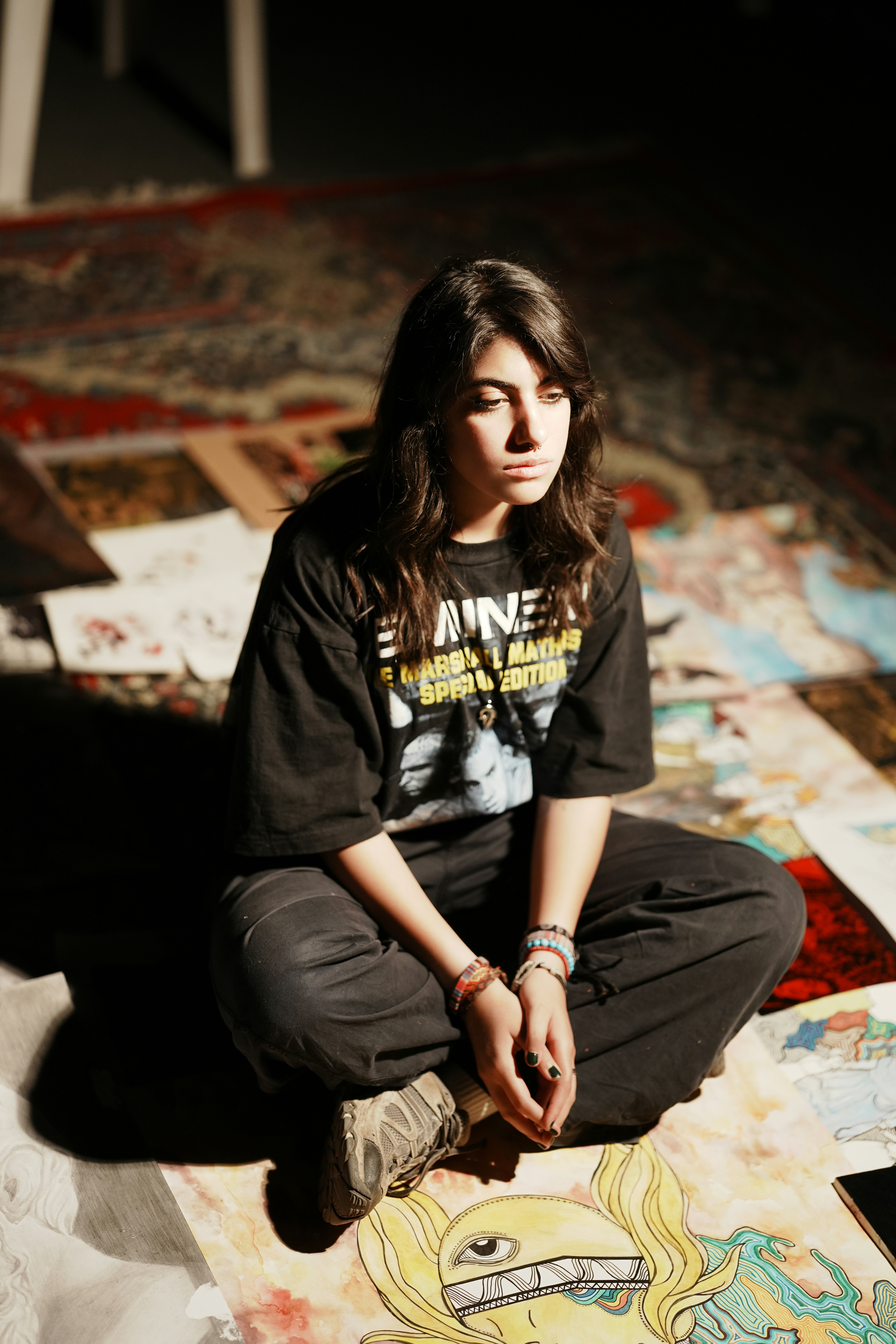 アート作品に囲まれて床に座る若い女性