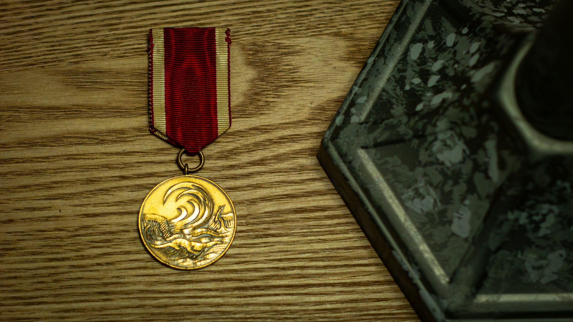 A gold medal with a red and white ribbon.