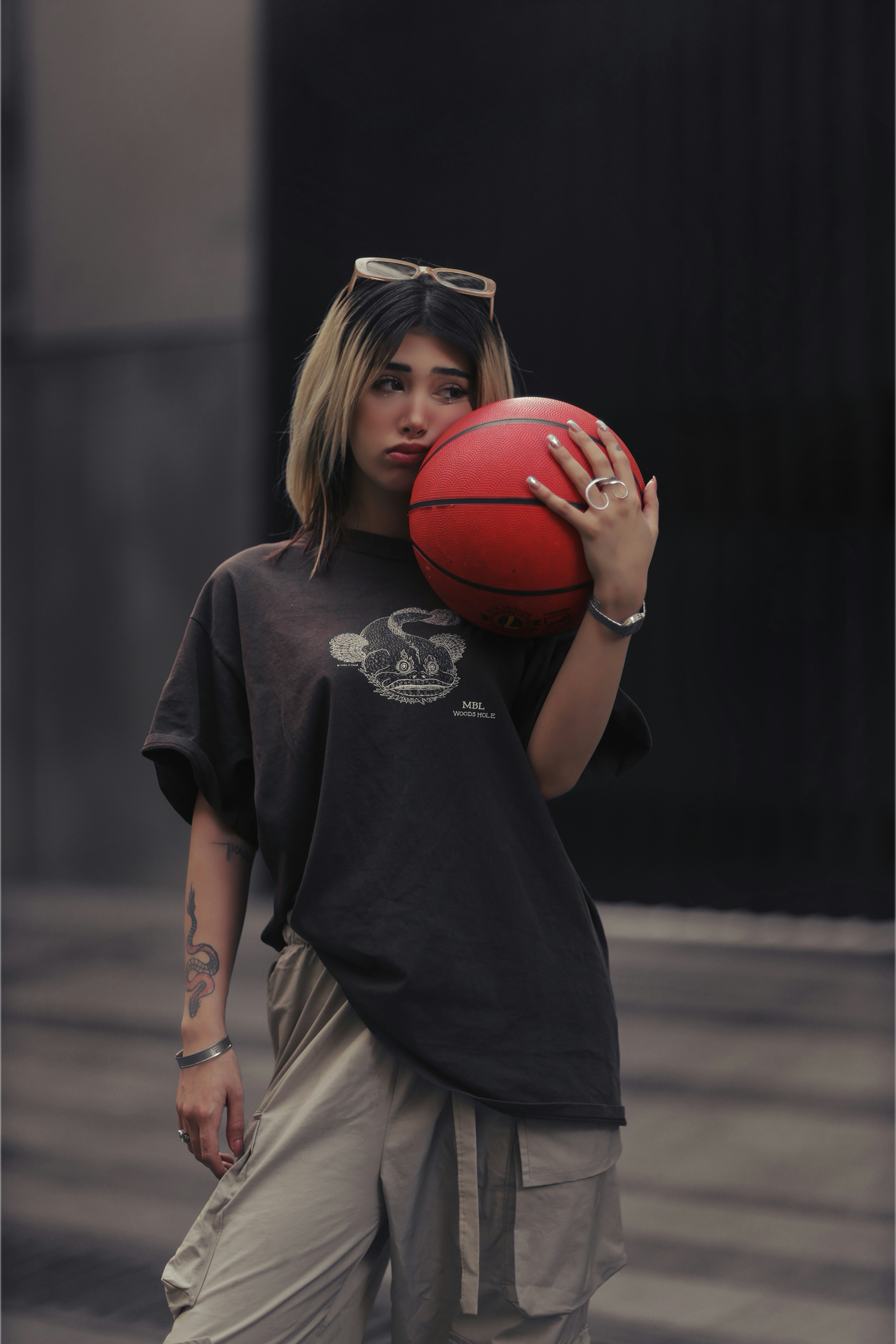 Giovane donna che tiene un pallone da basket con un broncio