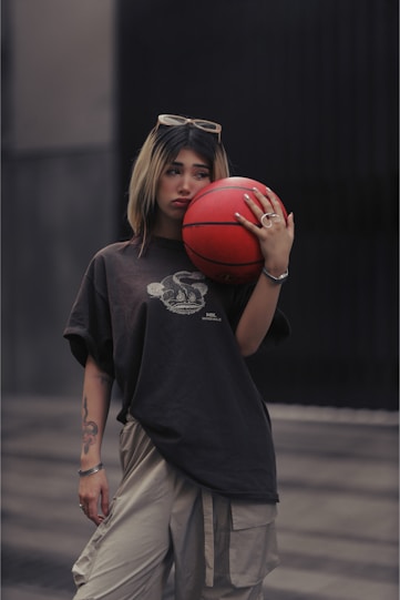 Young woman wearing a t-shirt holding a basketball with a pout