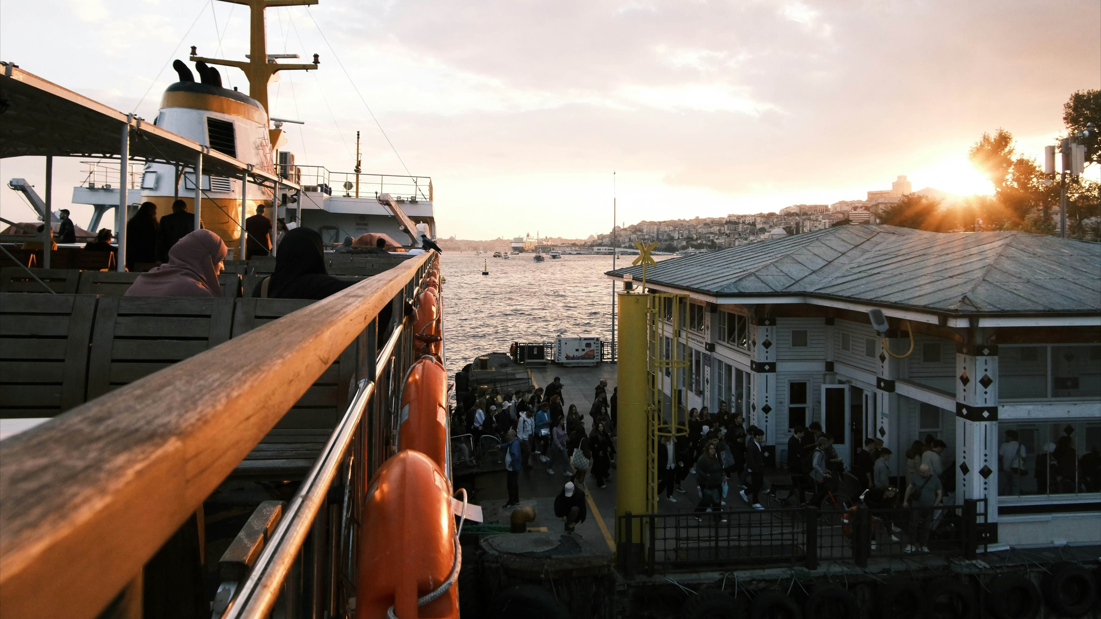 Ferry docked at a harbor during sunset with people waiting.
