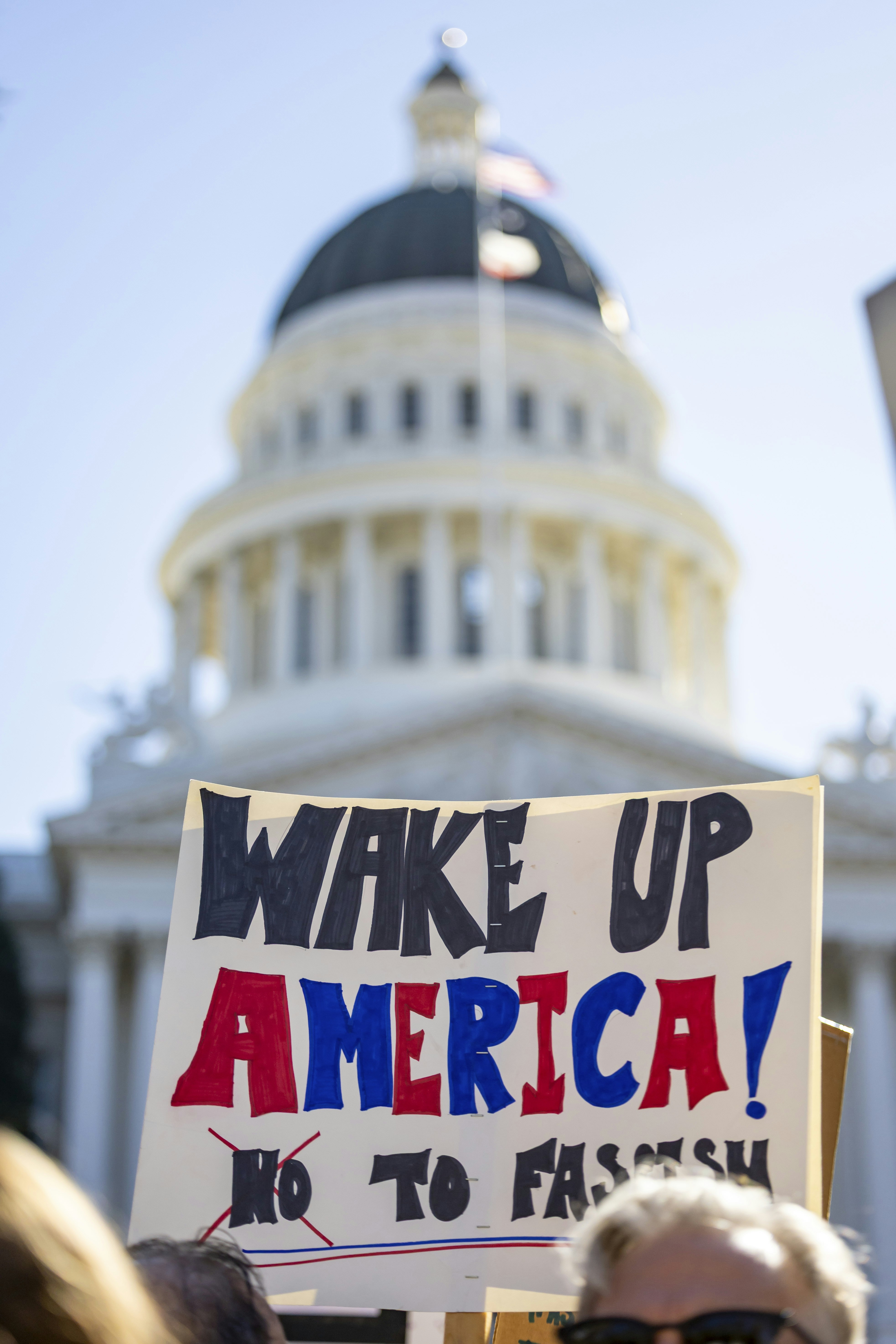 Protest sign reads "wake up america! no to fascism"