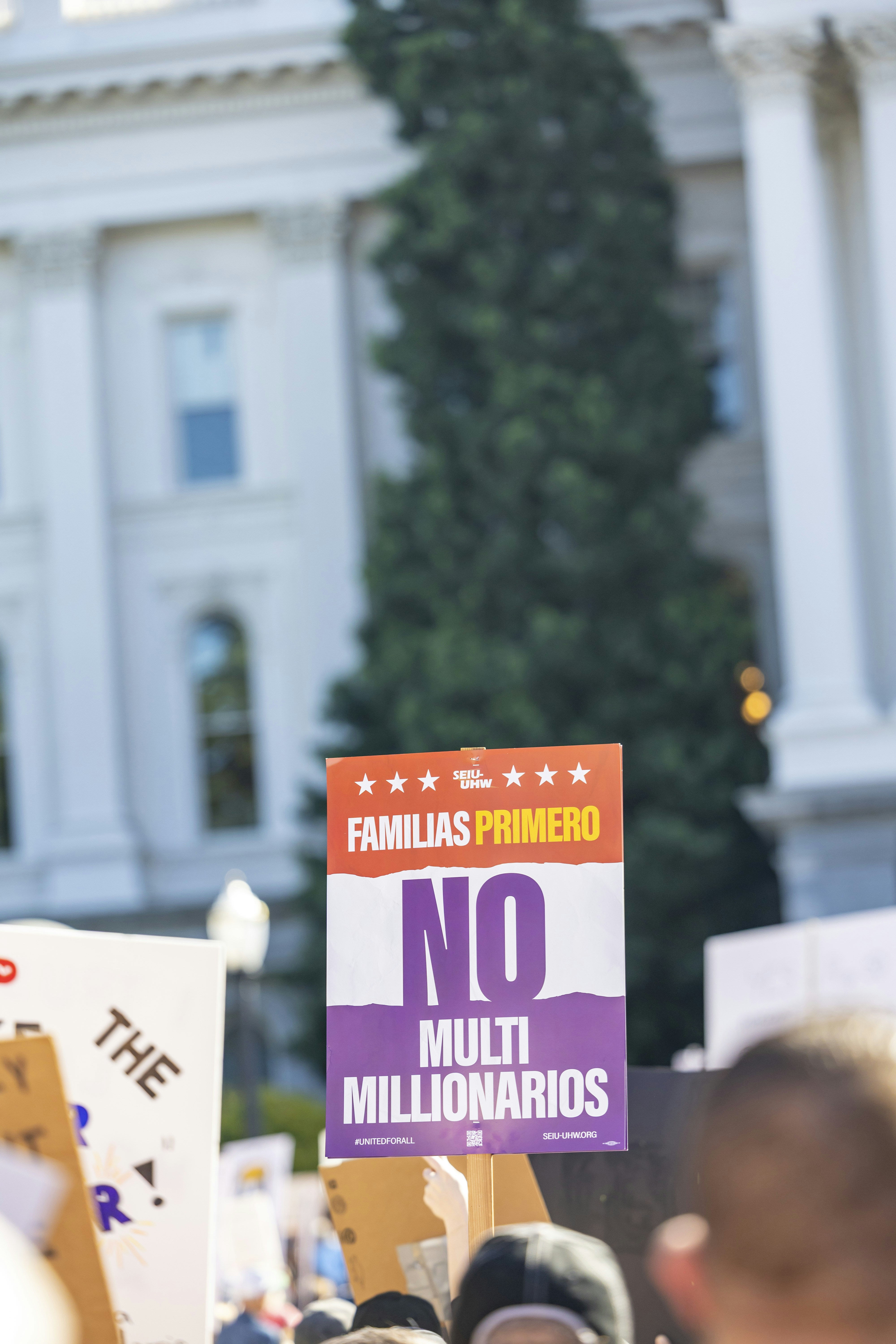 Protest sign reads 'familias primero no multi millonarios'.