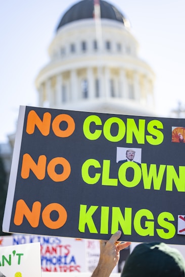 Protesters hold signs with "no cons, no clown, no kings".