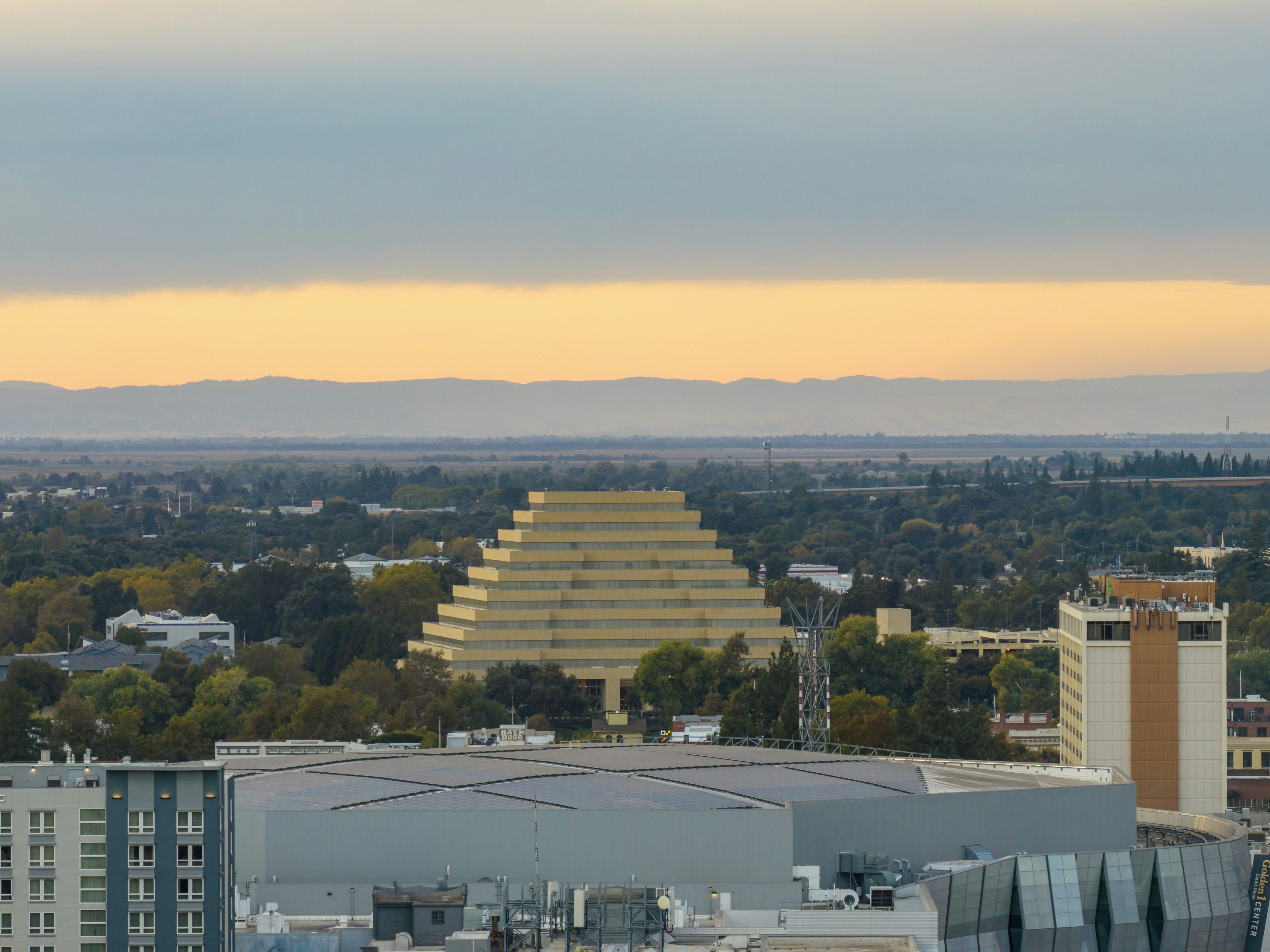 Pyramid building in a city with mountains behind.