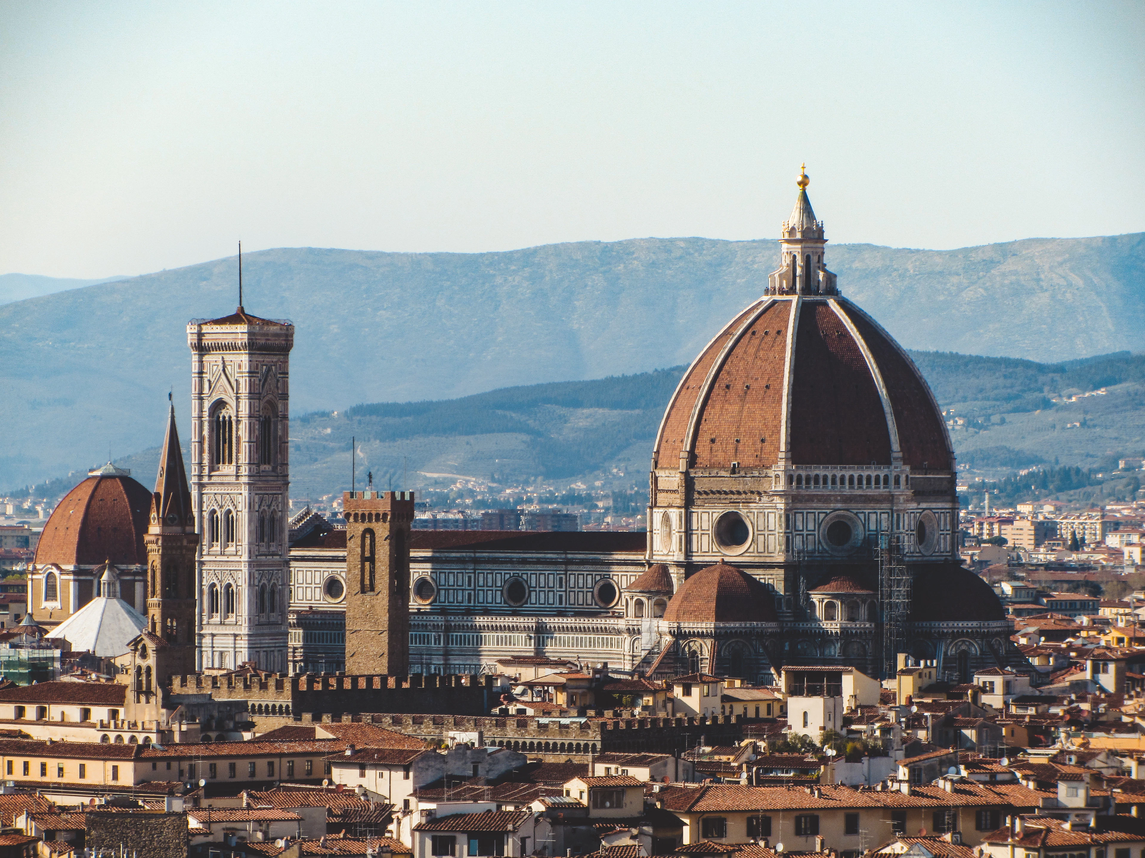 Florence's Duomo, with Brunelleschi's terracotta dome and Giotto's marble bell tower, rising above the city's rooftops against the Tuscan hills