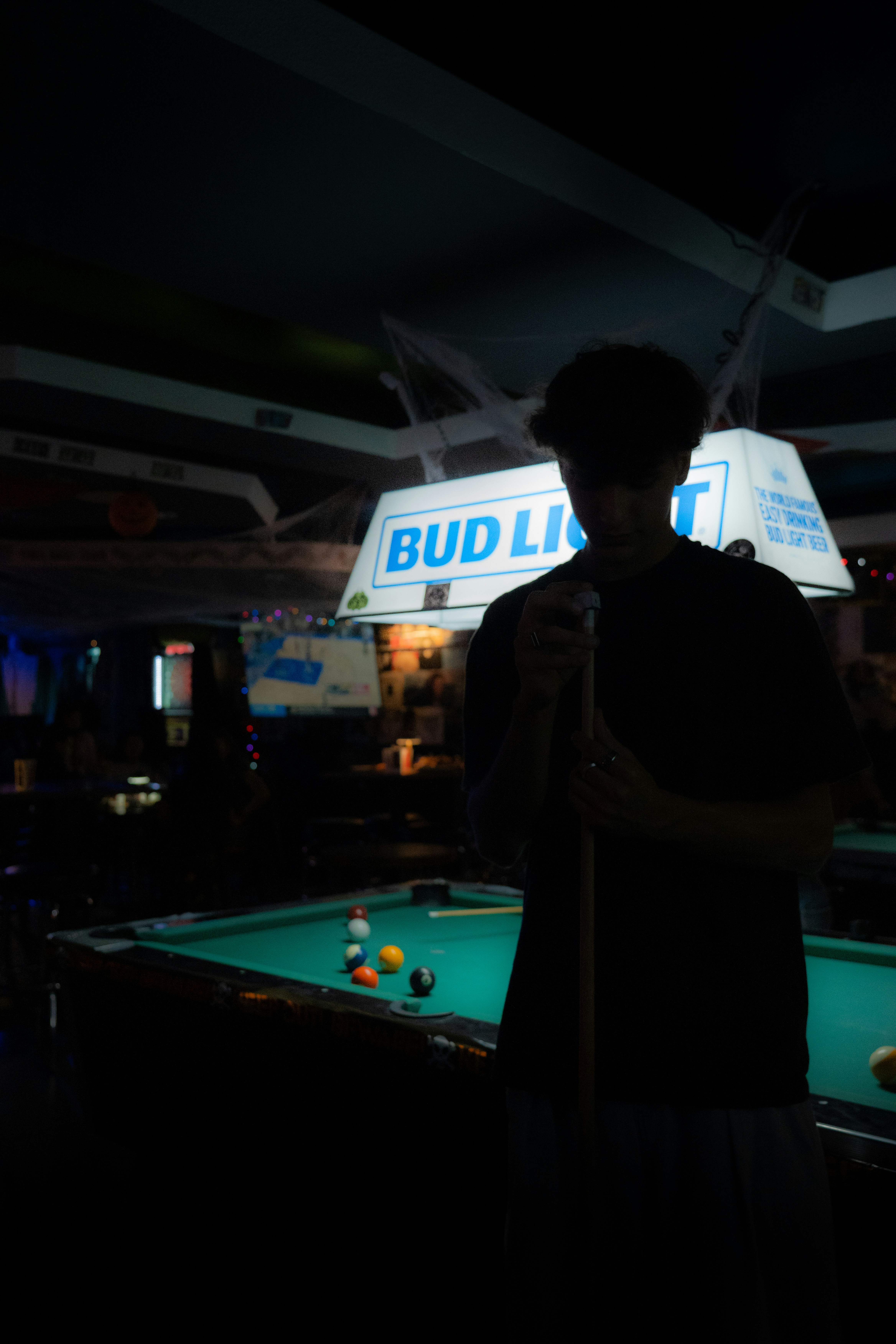 Hombre sosteniendo taco en la mesa de billar en el bar