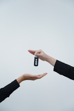Hands exchanging a car key against a light background