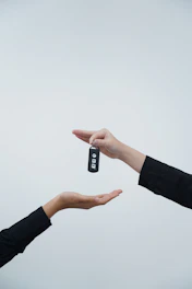 Hands exchanging a car key against a light background