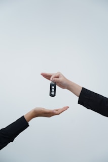 Hands exchanging a car key against a light background