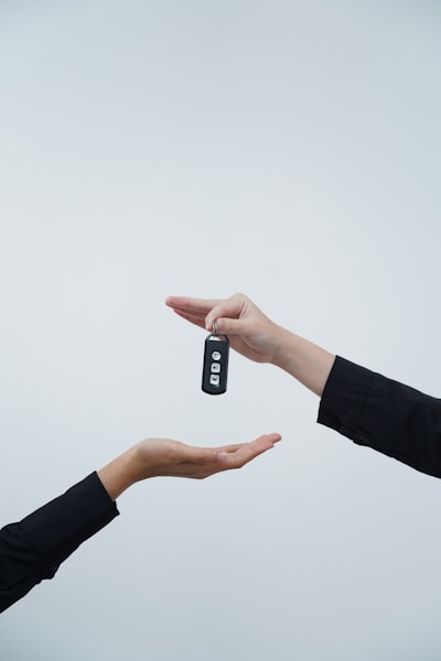 Hands exchanging a car key against a light background