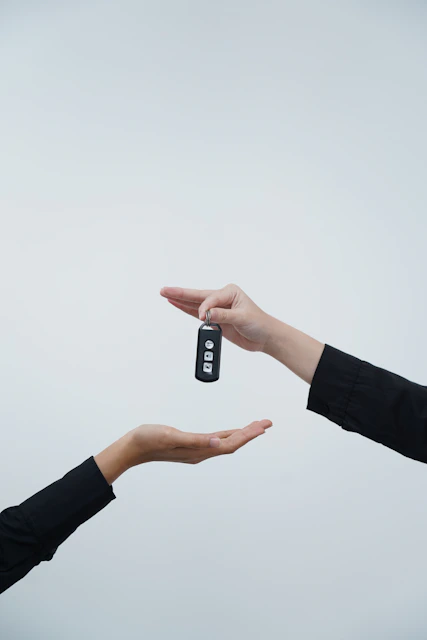 Hands exchanging a car key against a light background