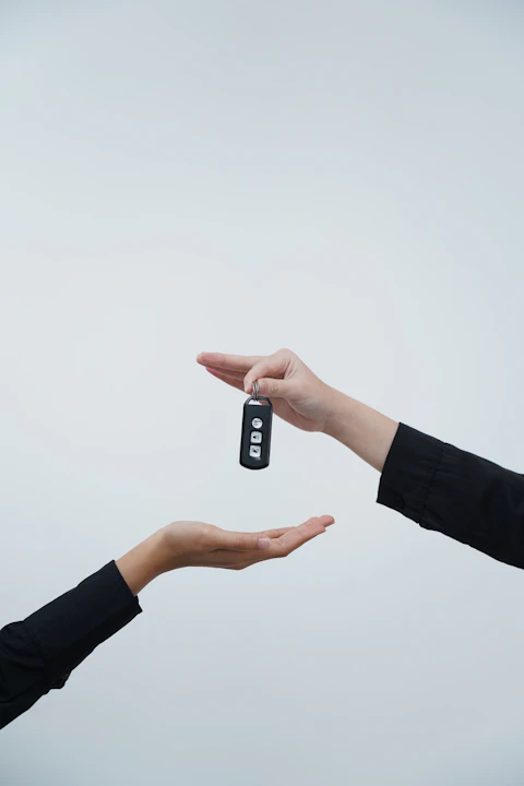 Hands exchanging a car key against a light background