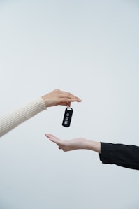 Hands exchanging car keys against a white background.