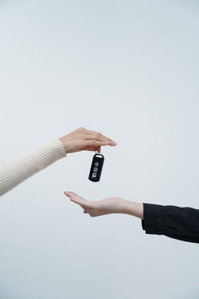 Hands exchanging car keys against a white background.