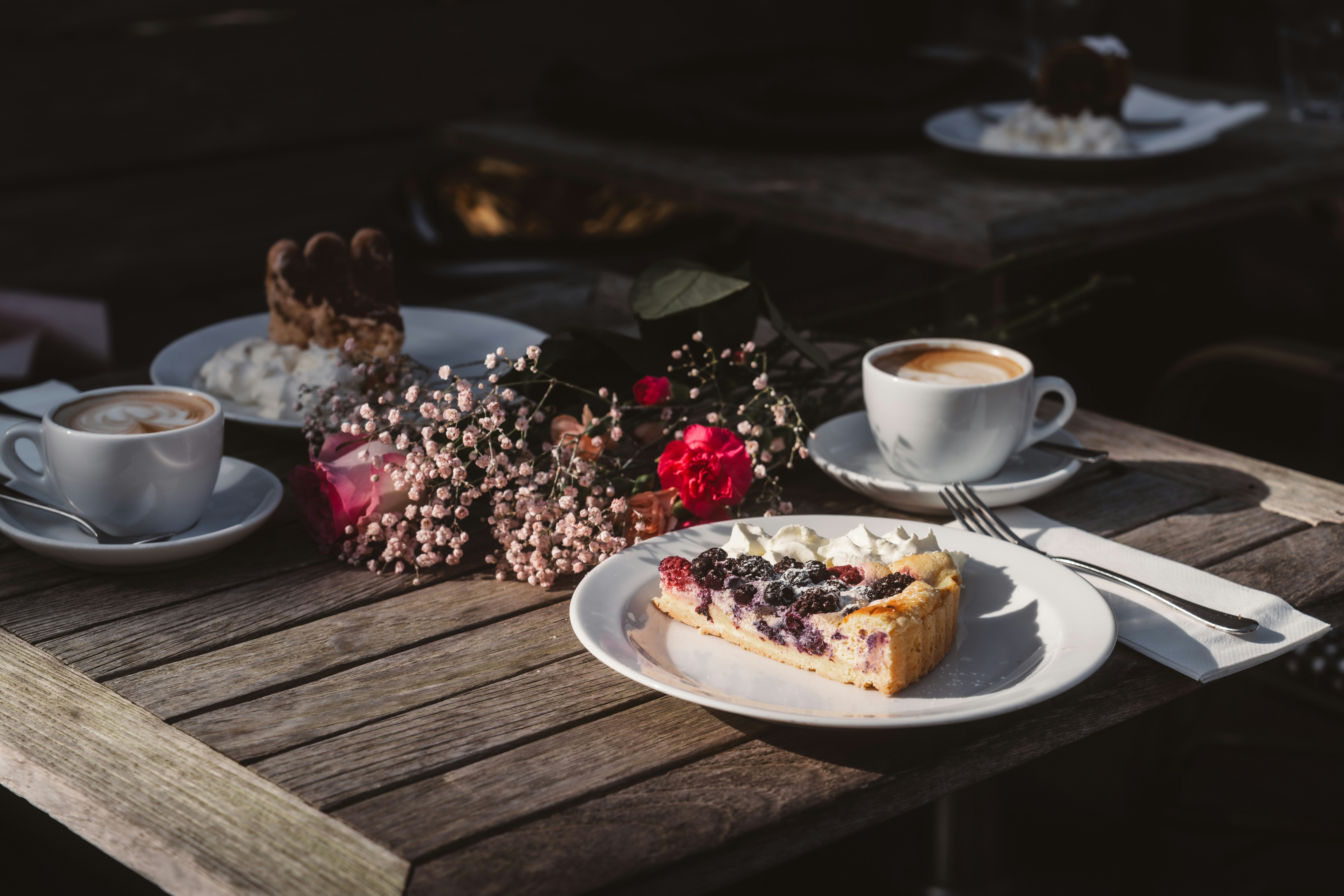 Sunlit morning hands with berry cake and latte
