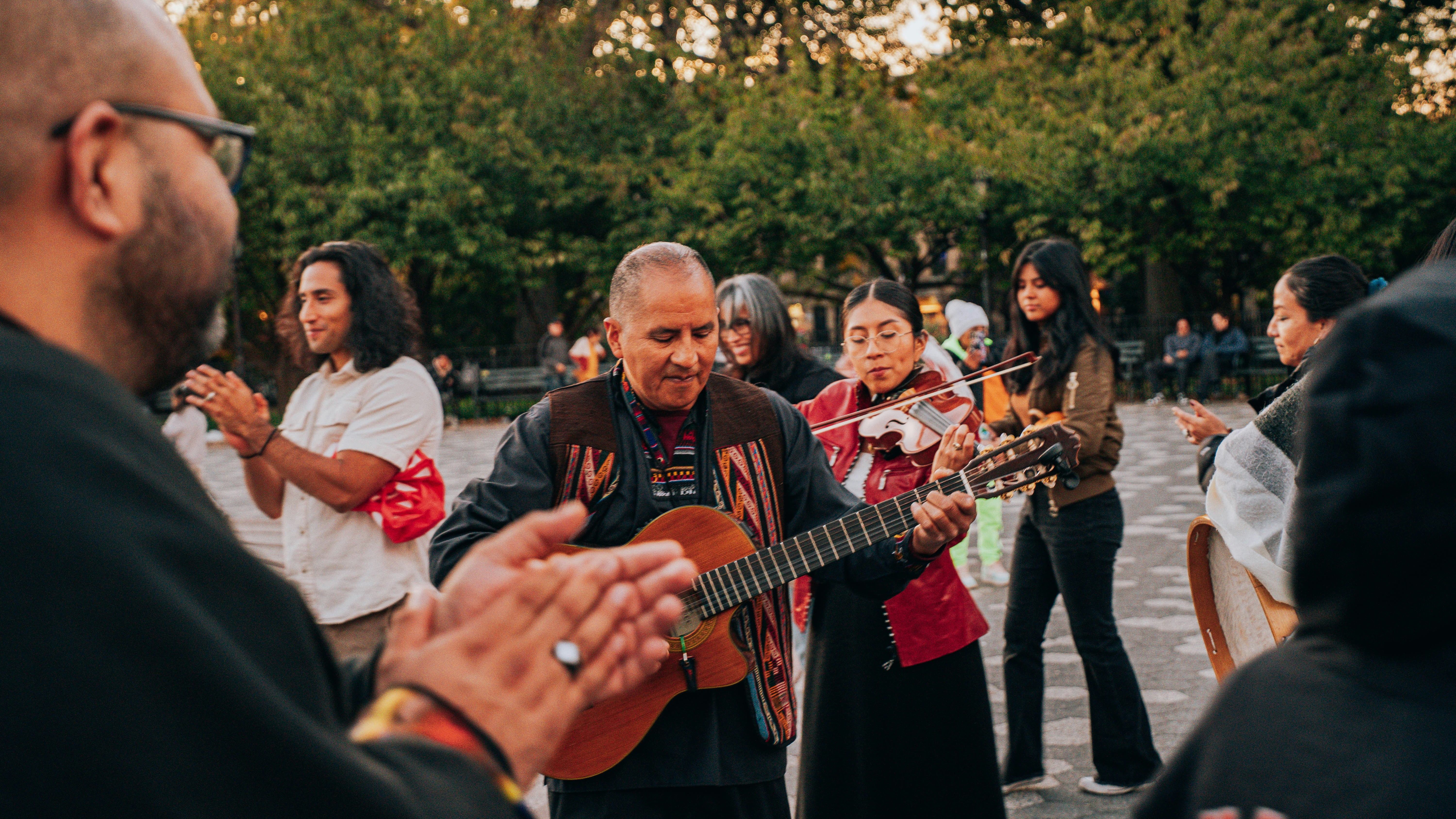 Musicians play guitar and sing for an outdoor crowd.